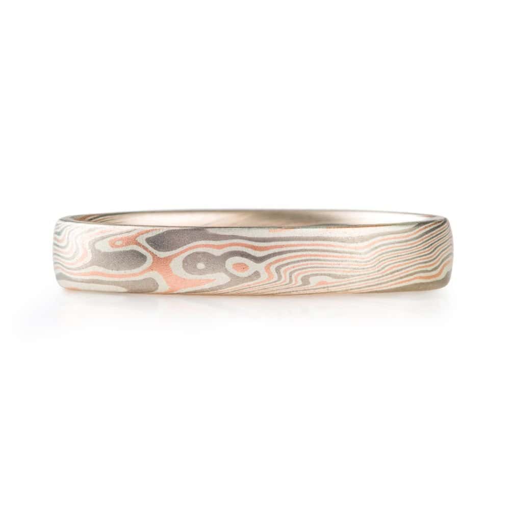 narrow twist patterned ring made with red gold, palladium and silver with a smooth finish
