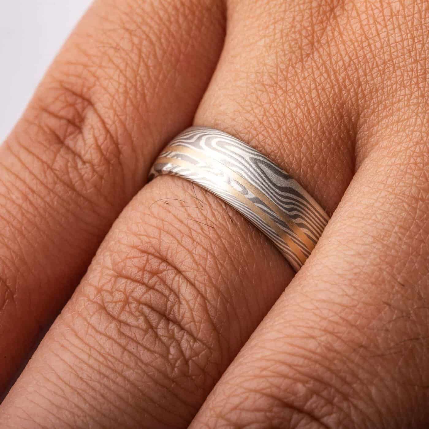 mokume gane silvery ring with two yellow gold lines running perfectly parallel around the band