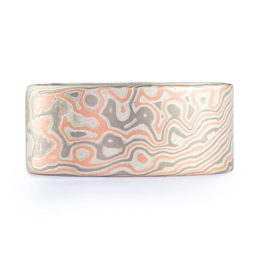 Wide ring with a flat profile, made with red gold, palladium (gray) and silver (light gray), in a twisting and speckled style pattern. Â