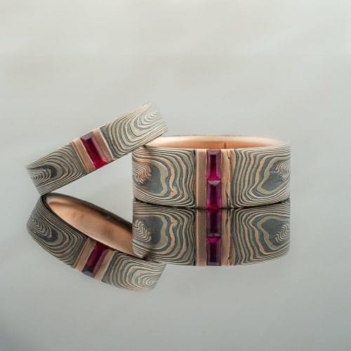  8mm Embers Mokume Gane wedding band with channel set diamonds and sapphires, etched finish, flat profile, and 14k red gold, palladium, and sterling silver.