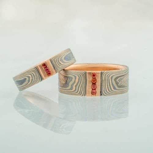 8mm Embers Mokume Gane wedding band with channel set diamonds and sapphires, etched finish, flat profile, and 14k red gold, palladium, and sterling silver.