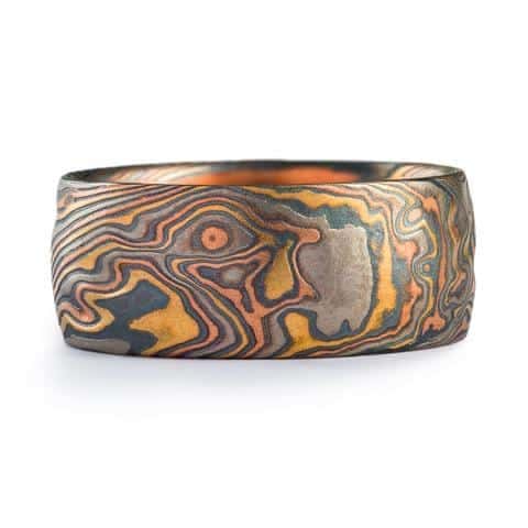 Wide mokume gane ring with a slightly domed profile, made with red and yellow gold, palladium and oxidized silver.