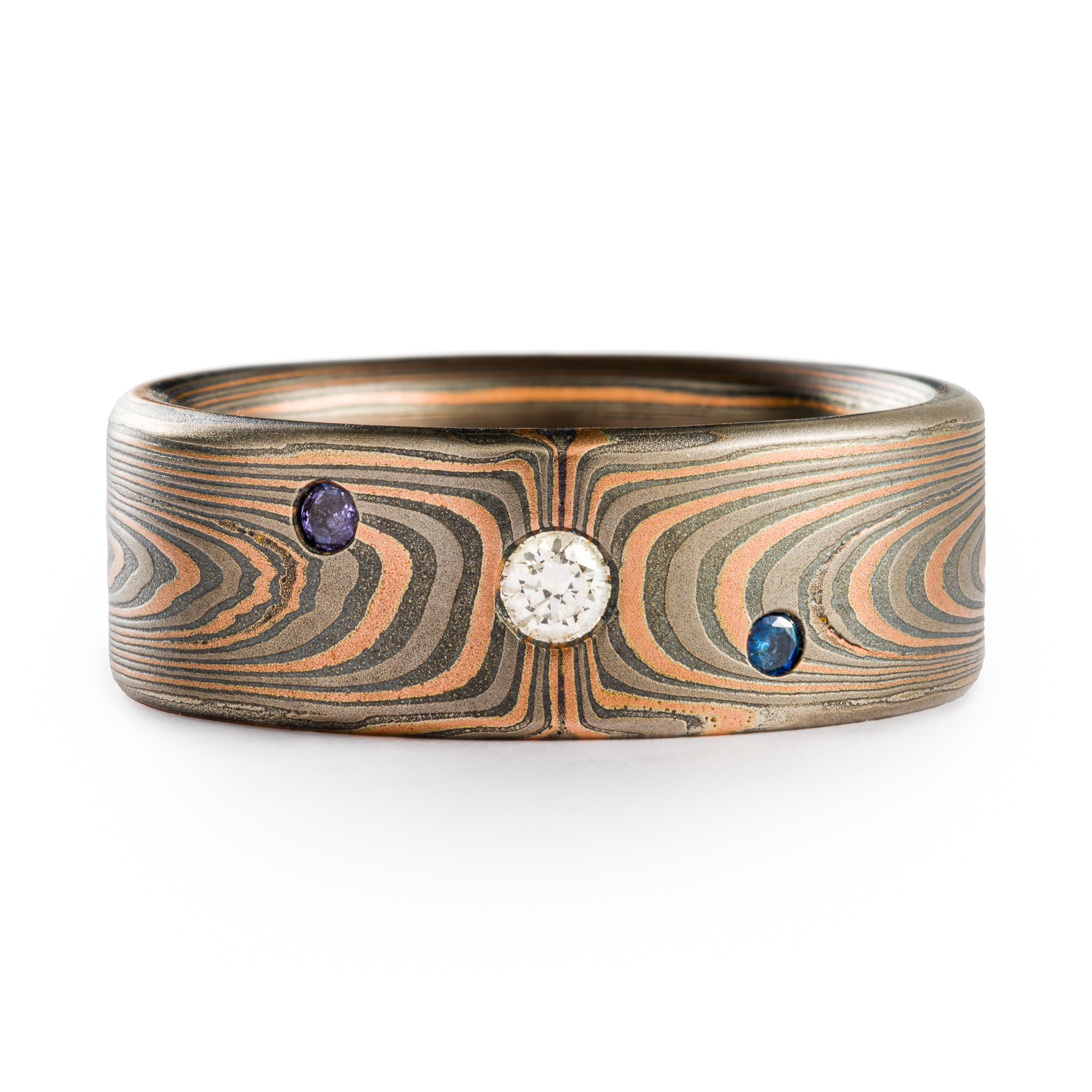 Mokume Gane 8mm wide ring made by arn krebs, vortex pattern and embers palette, flat profile, with flush set stones. The embers palette is made of red gold palladium and silver and the ring has been etched and oxidized.