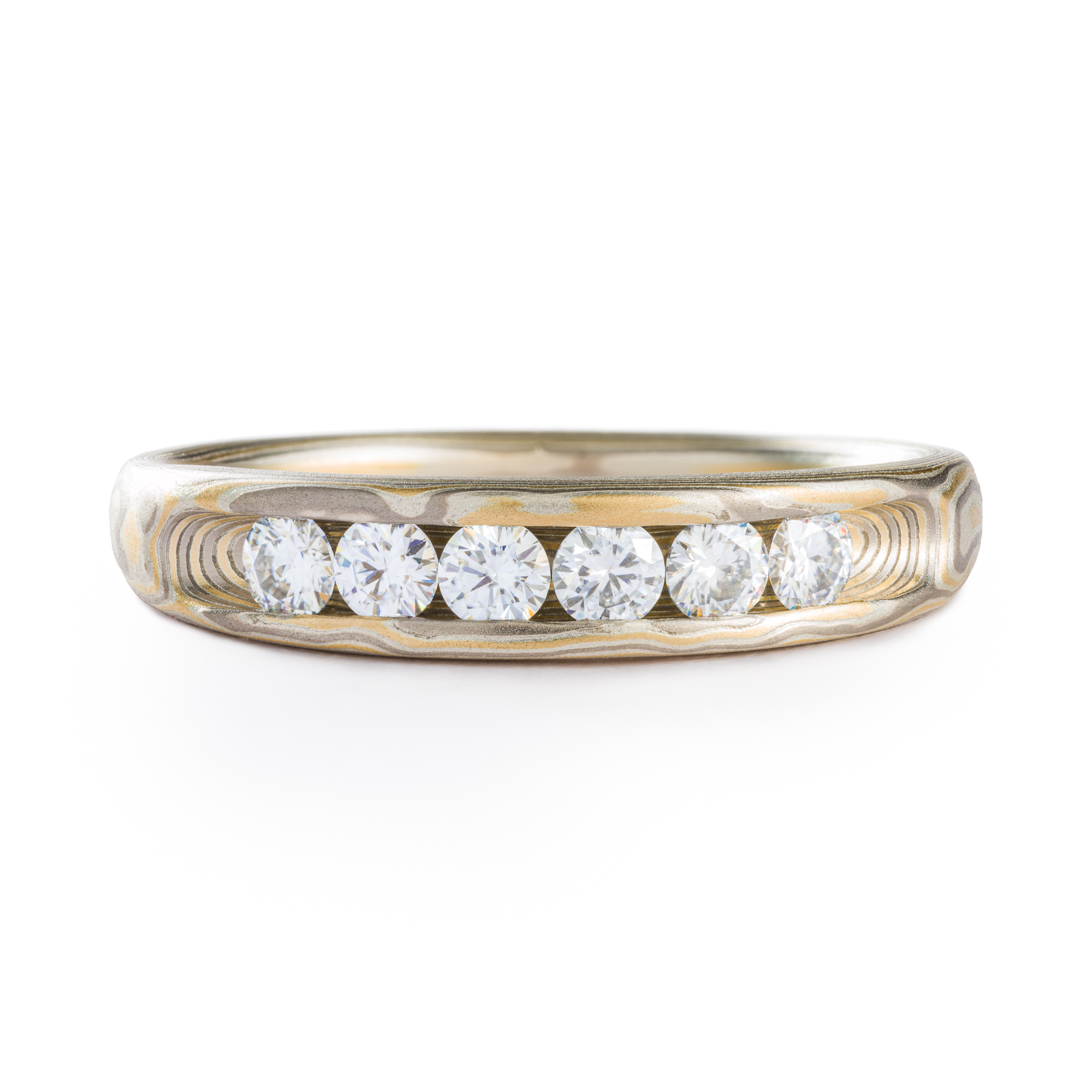 Mokume gane ring made by arn krebs, patterning is made up of alternating layers of yellow gold, silver and palladium, the pattern resembles the grain of a piece of wood, and the front of the ring is largely taken up by 6 round moissanite stones (similar looking to diamonds), nested in a carved groove called a channel setting