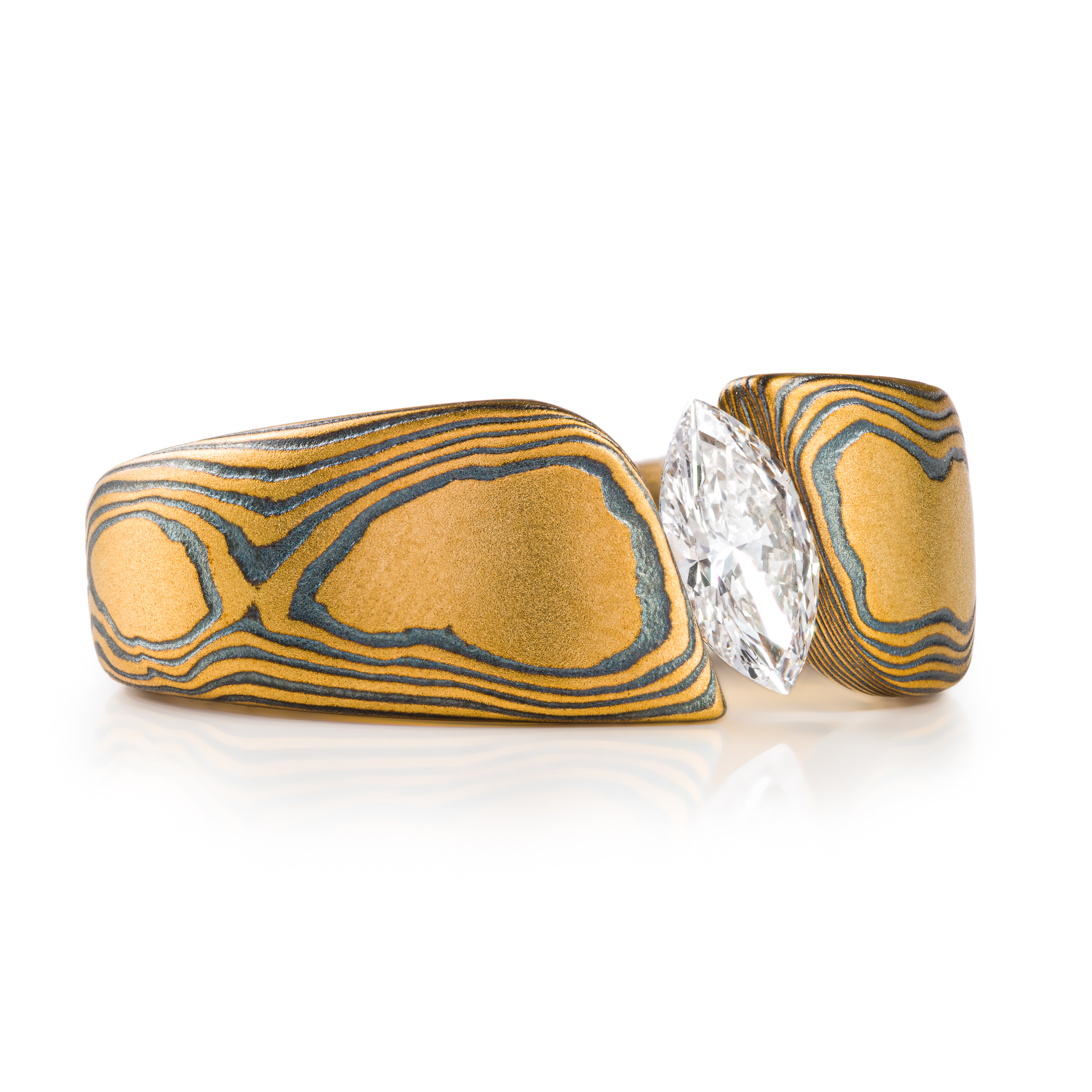 large and bold mokume gane tension set ring, featuring a beautiful marquise cut diamond set at an angle