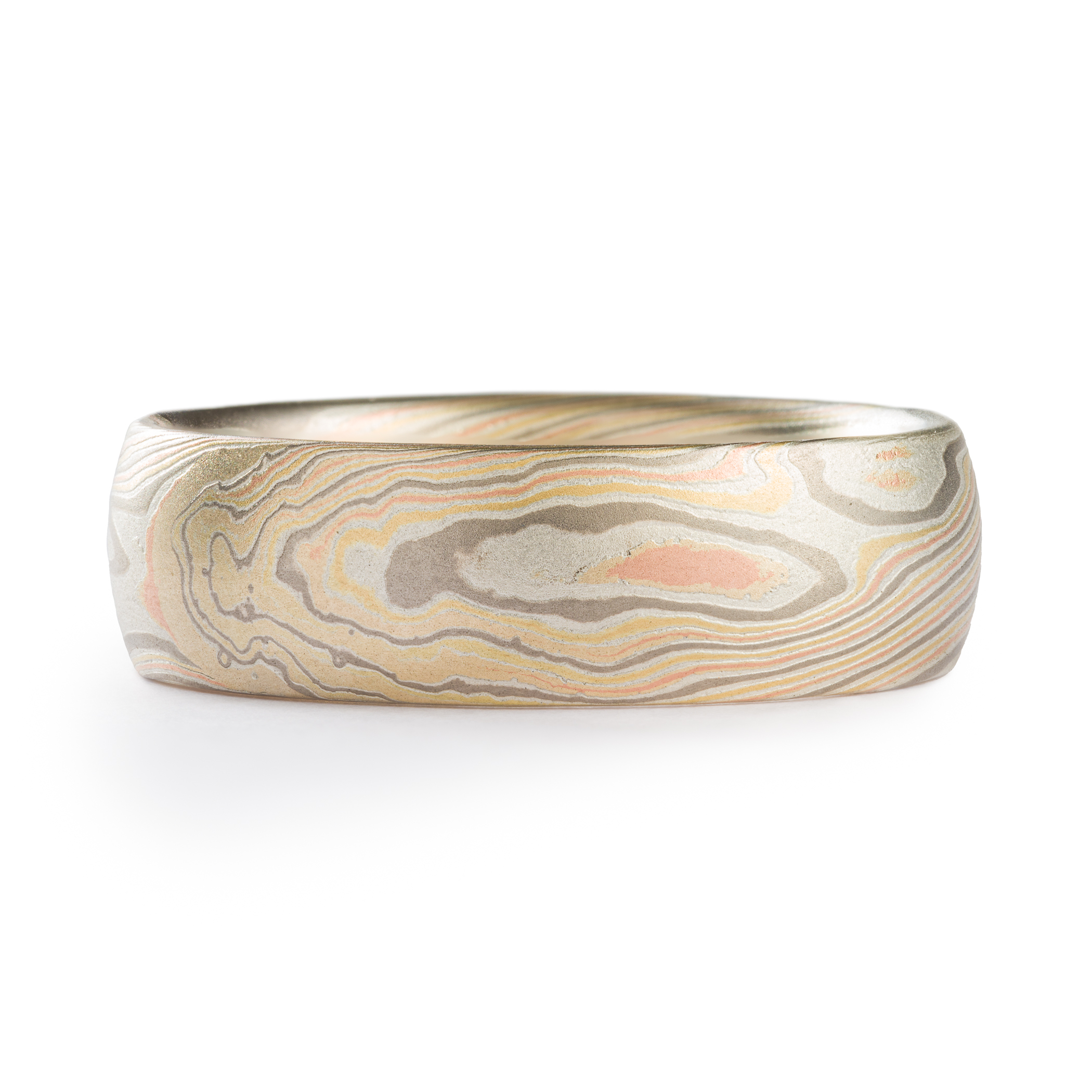 mens ring in mokume gane band with domed profile, made in a twisted pattern with diagonal lines running across, with red and yellow gold, palladium, and etched silver