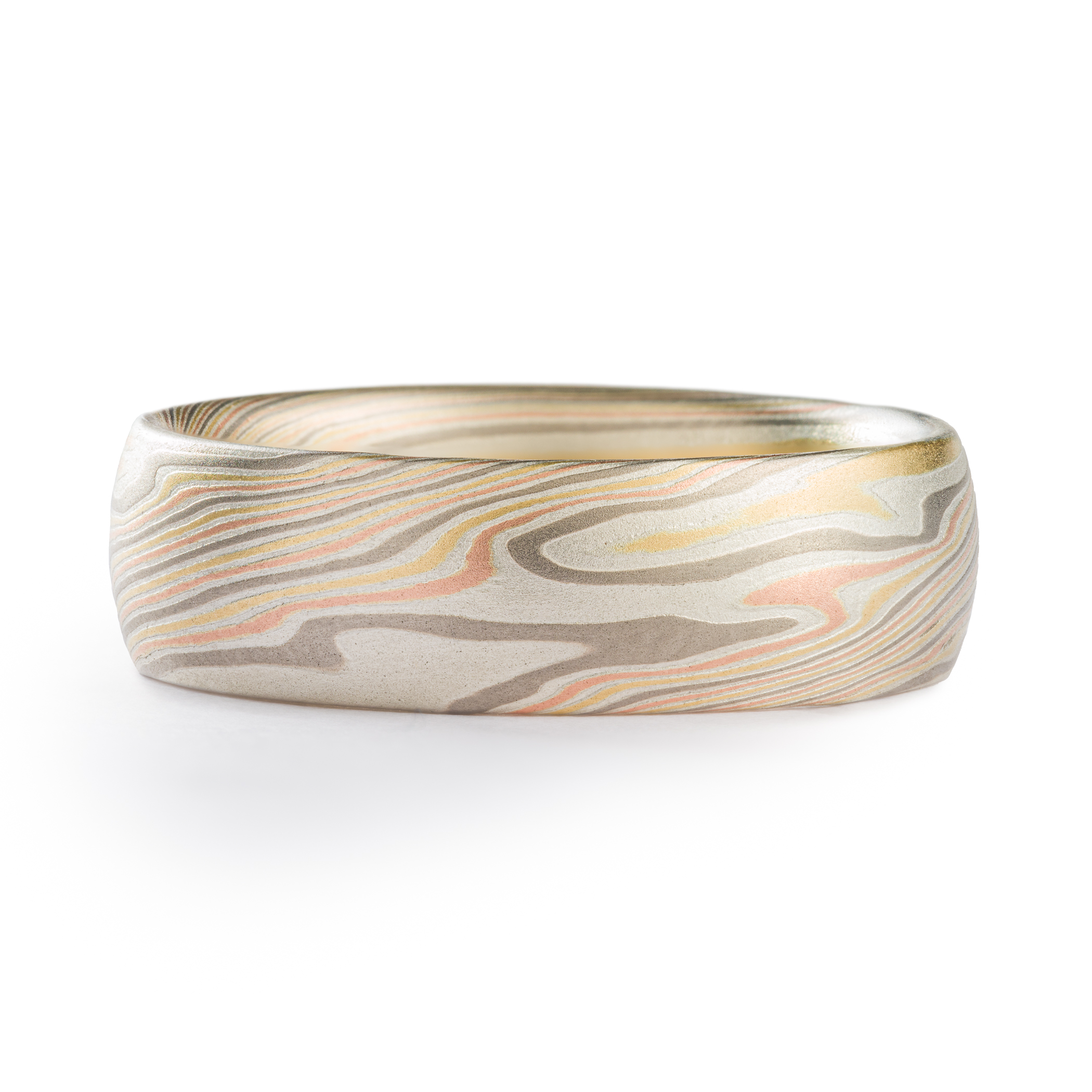 mens ring in mokume gane band with domed profile, made in a twisted pattern with diagonal lines running across, with red and yellow gold, palladium, and etched silver