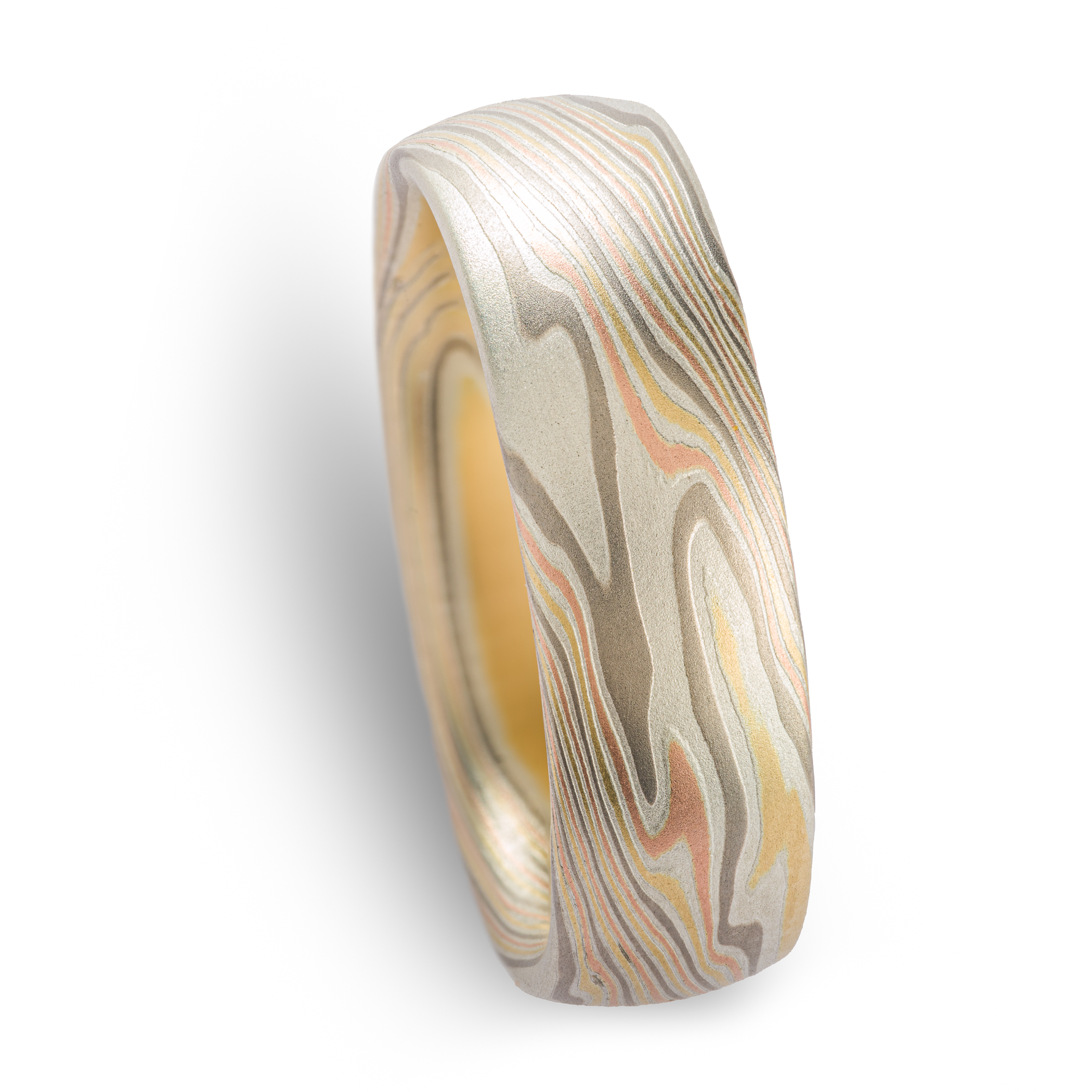 mens ring in mokume gane band with domed profile, made in a twisted pattern with diagonal lines running across, with red and yellow gold, palladium, and etched silver