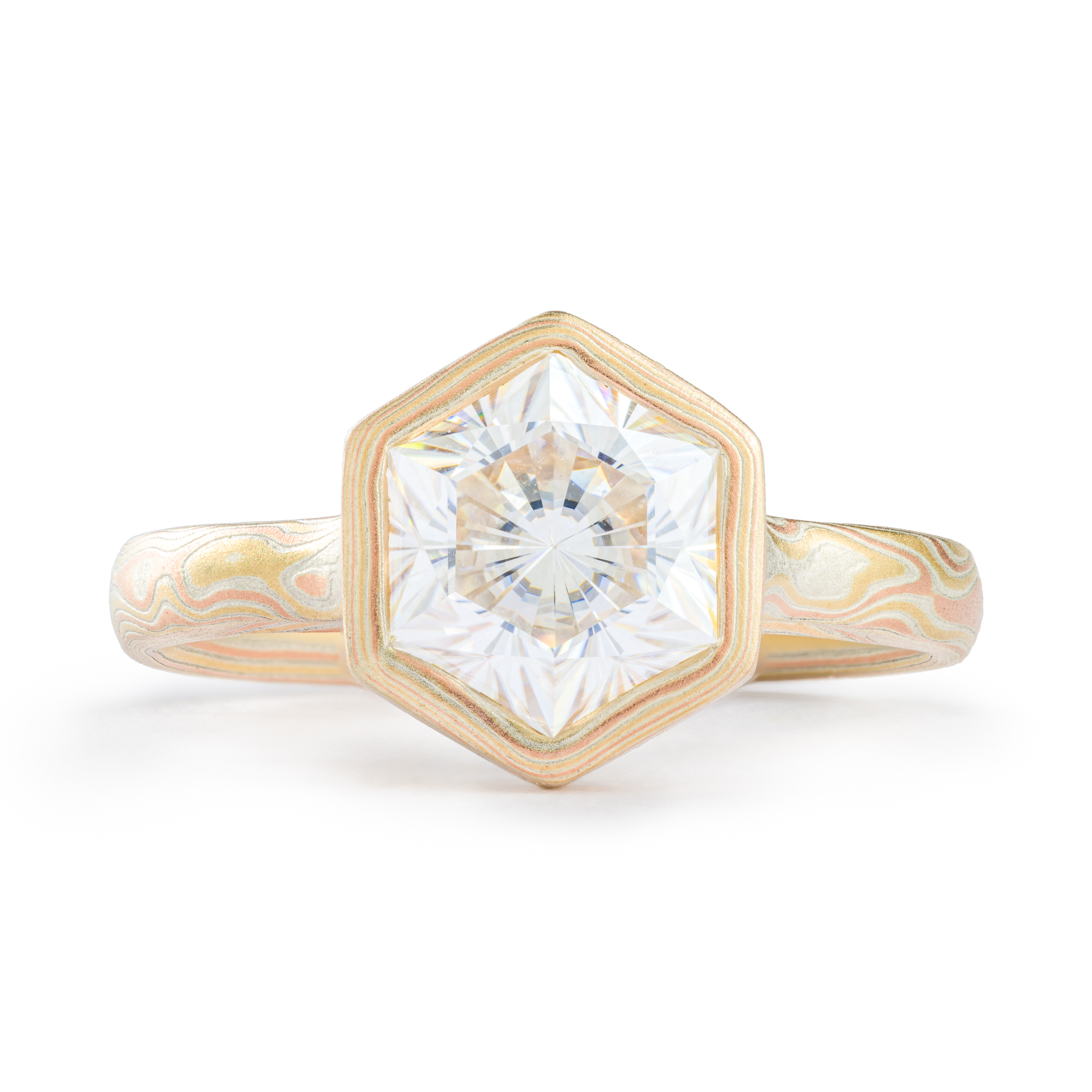 Mokume gane engagement ring arn krebs, thin band with a large white stone, hexagon cut, at the center. The stone is surrounded by a handmade bezel in mokume as well, all yellow and red gold and silver