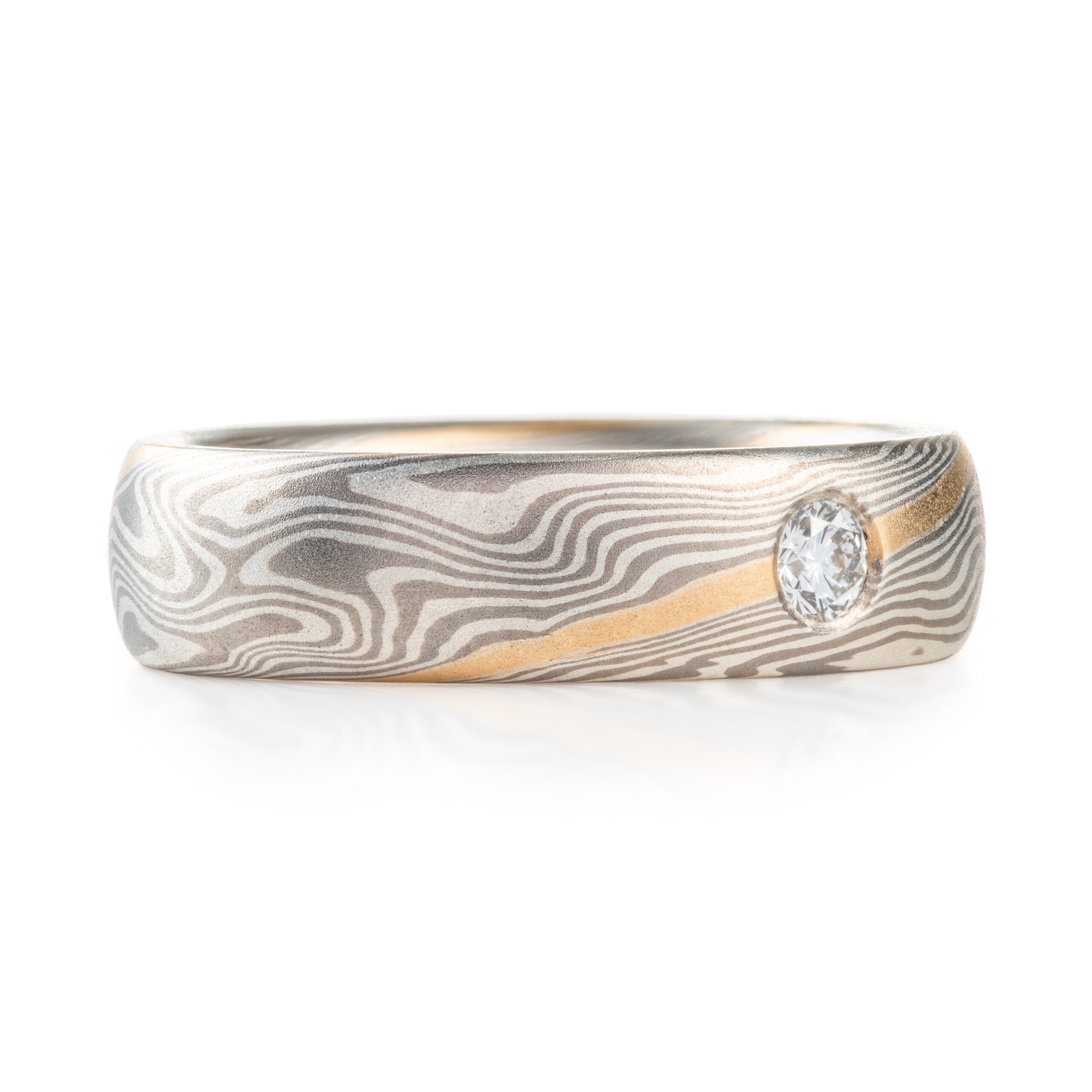 mokume gane band with a flush set diamond and an added yellow gold stratum layer