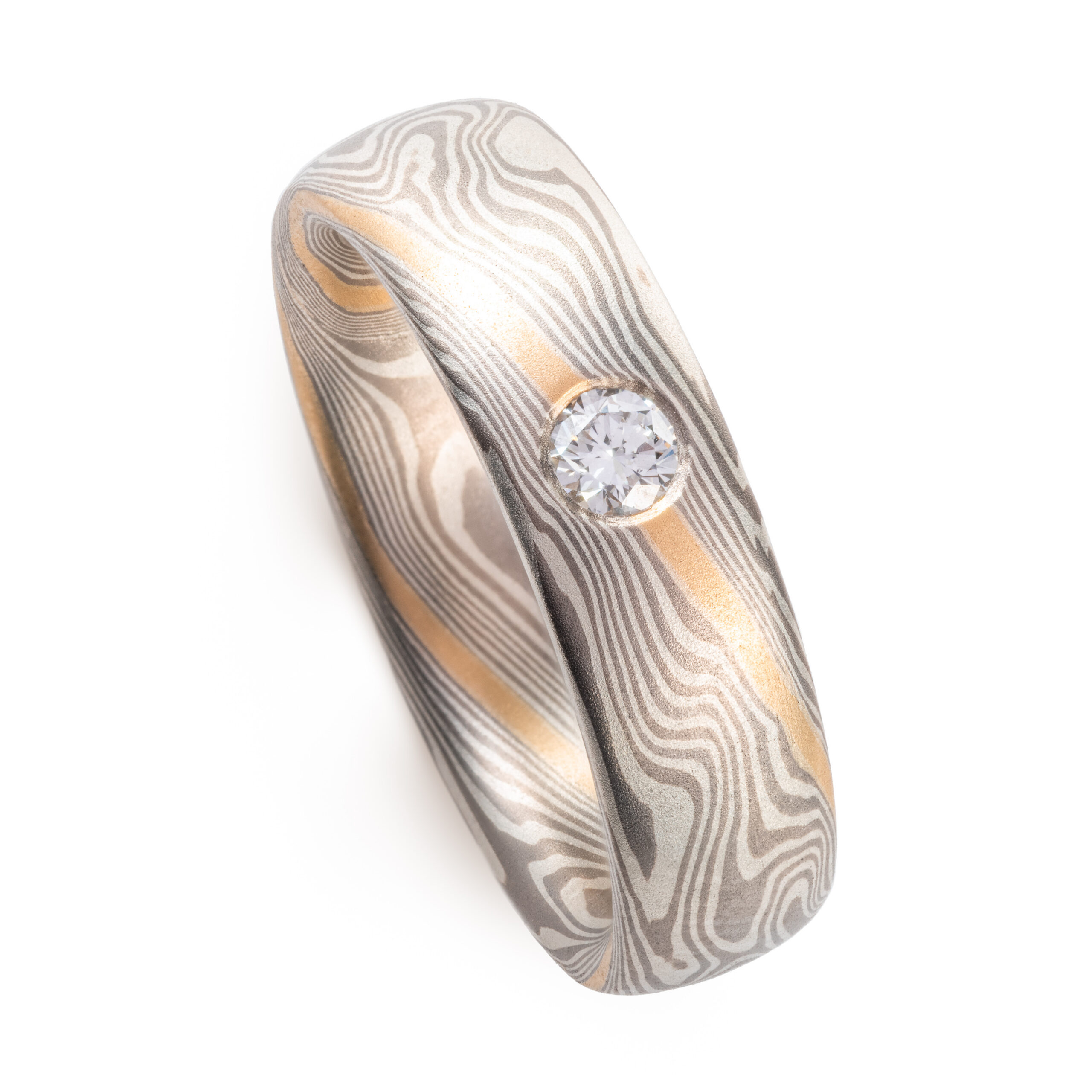 mokume gane band with a flush set diamond and an added yellow gold stratum layer