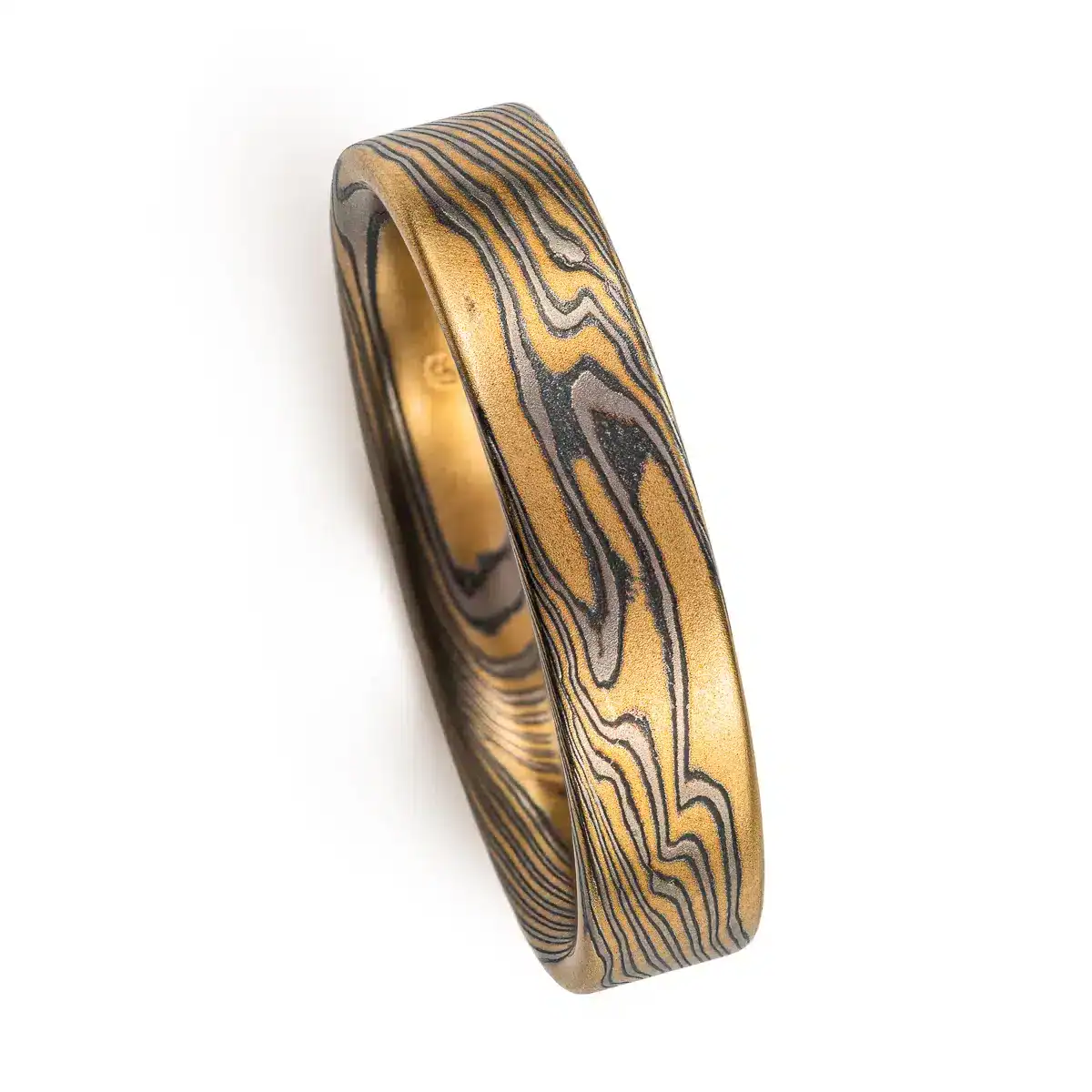 rustic gold mokume gane band with a flat profile ring, high contrast with oxidized silver