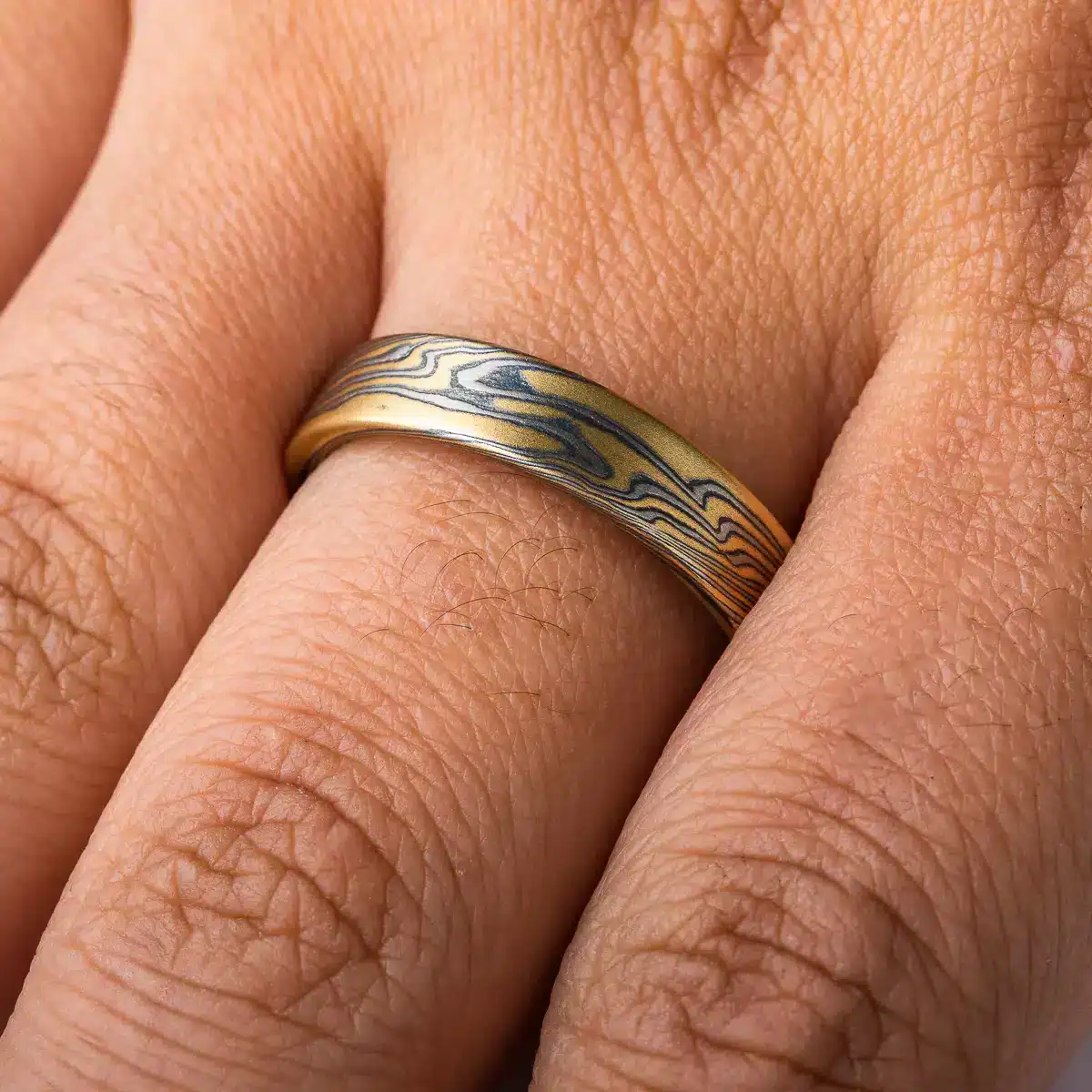 rustic gold mokume gane band with a flat profile ring, high contrast with oxidized silver