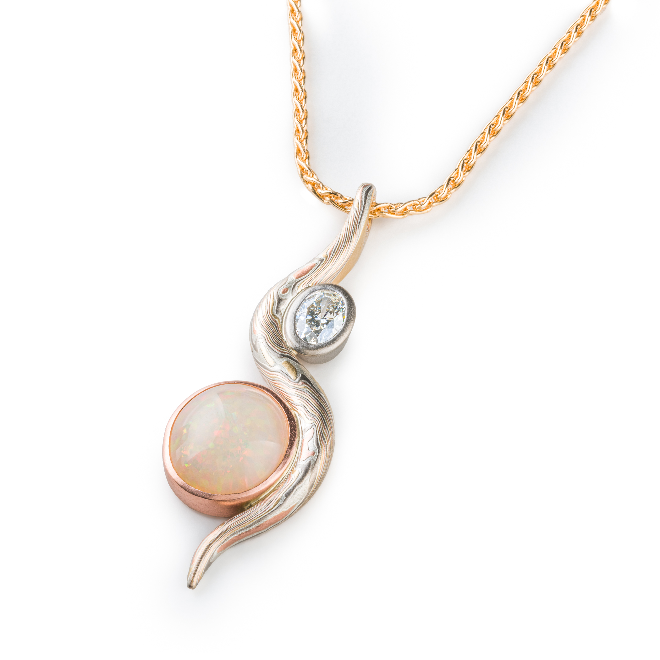 Elegant pendant made with a slender snake of patterned mokume gane gently curling around two oval shaped stones.