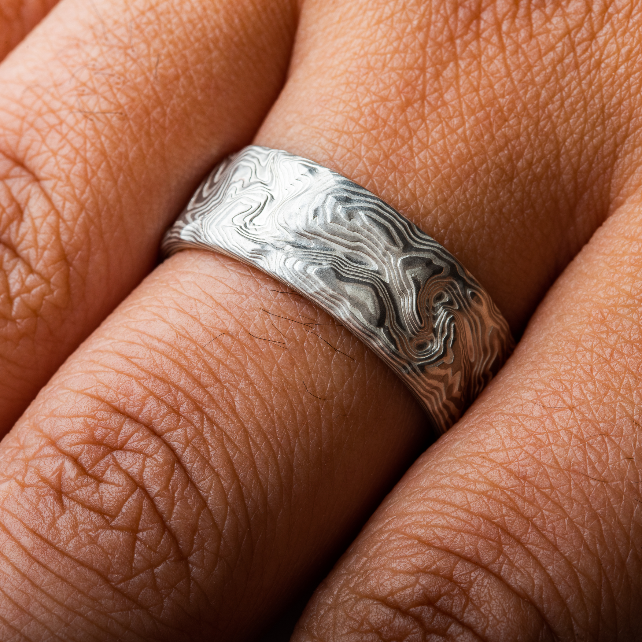 Custom carved mokume gane ring where the pattern resembles the topographic map of a specific place. Made with palladium and etched silver.