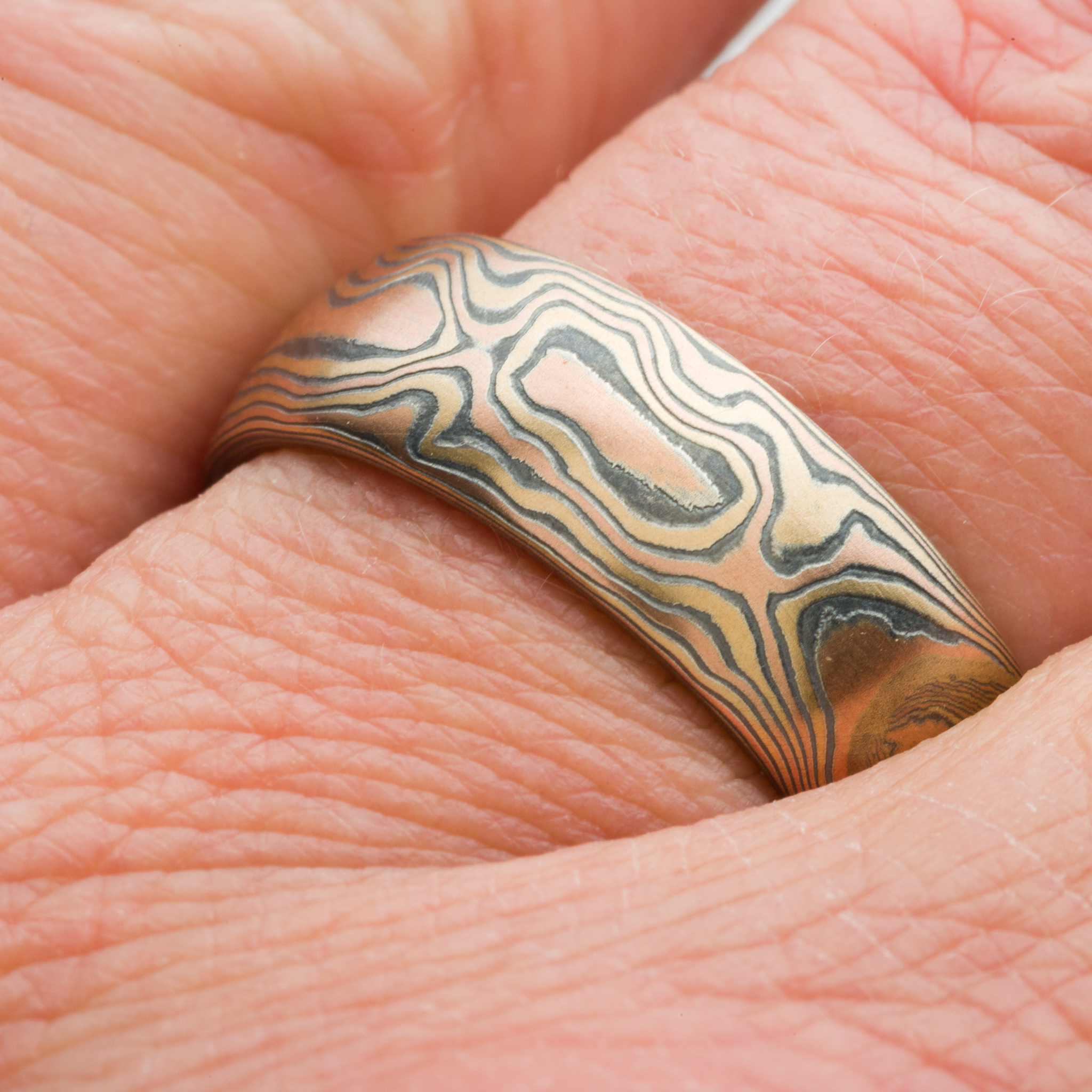 warm toned mokume gane band patterned to look like woodgrain