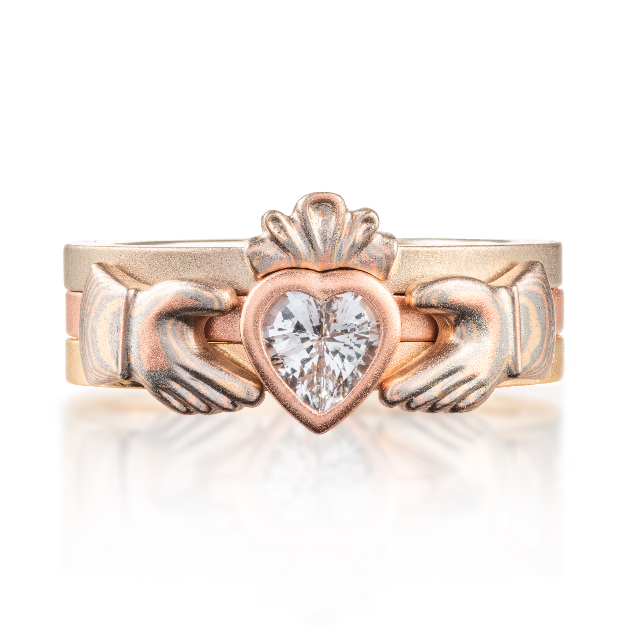 custom made three part claddagh ring, with mokume hands holding a white sapphire heart shaped stone, with a mokume crown on top of the stone