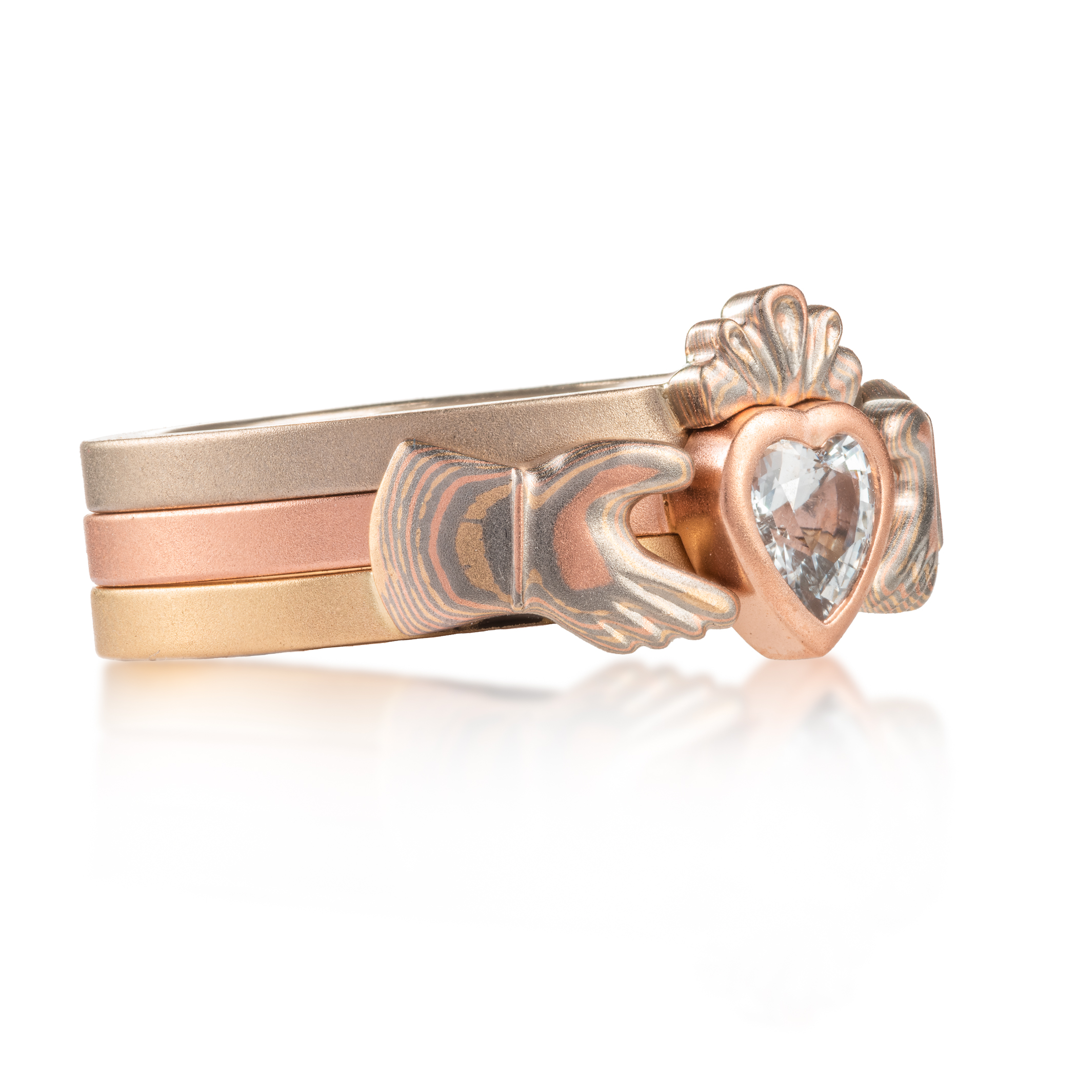 custom made three part claddagh ring, with mokume hands holding a white sapphire heart shaped stone, with a mokume crown on top of the stone