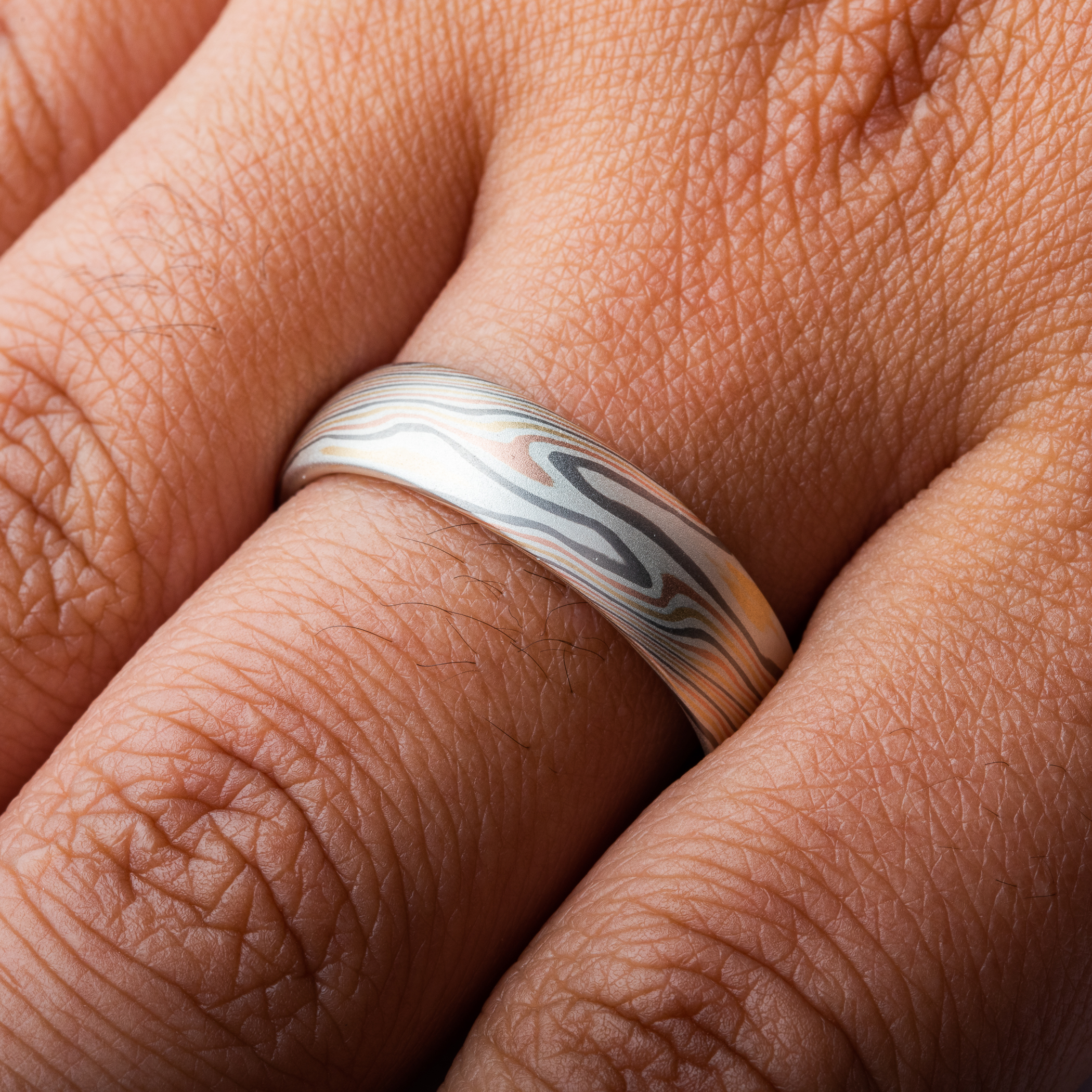 Mokume gane wedding band made in twisting pattern, made with yellow and red gold, palladium and silver.