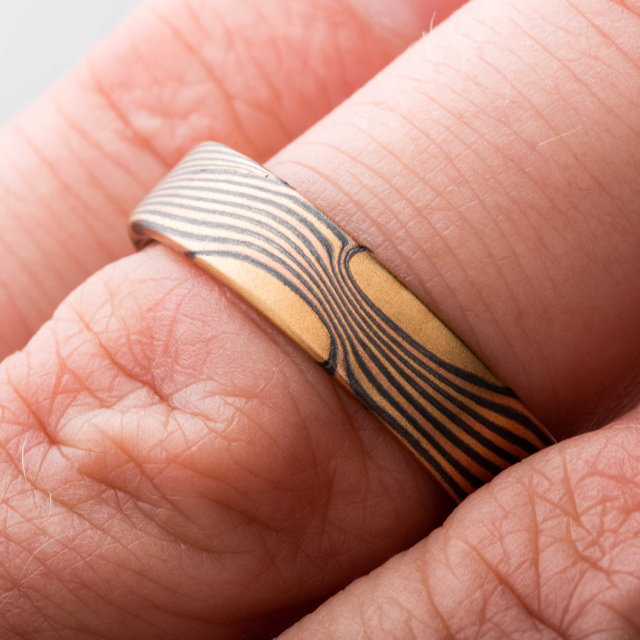 Flat profile mokume men's ring made with gold, red gold and oxidized silver.