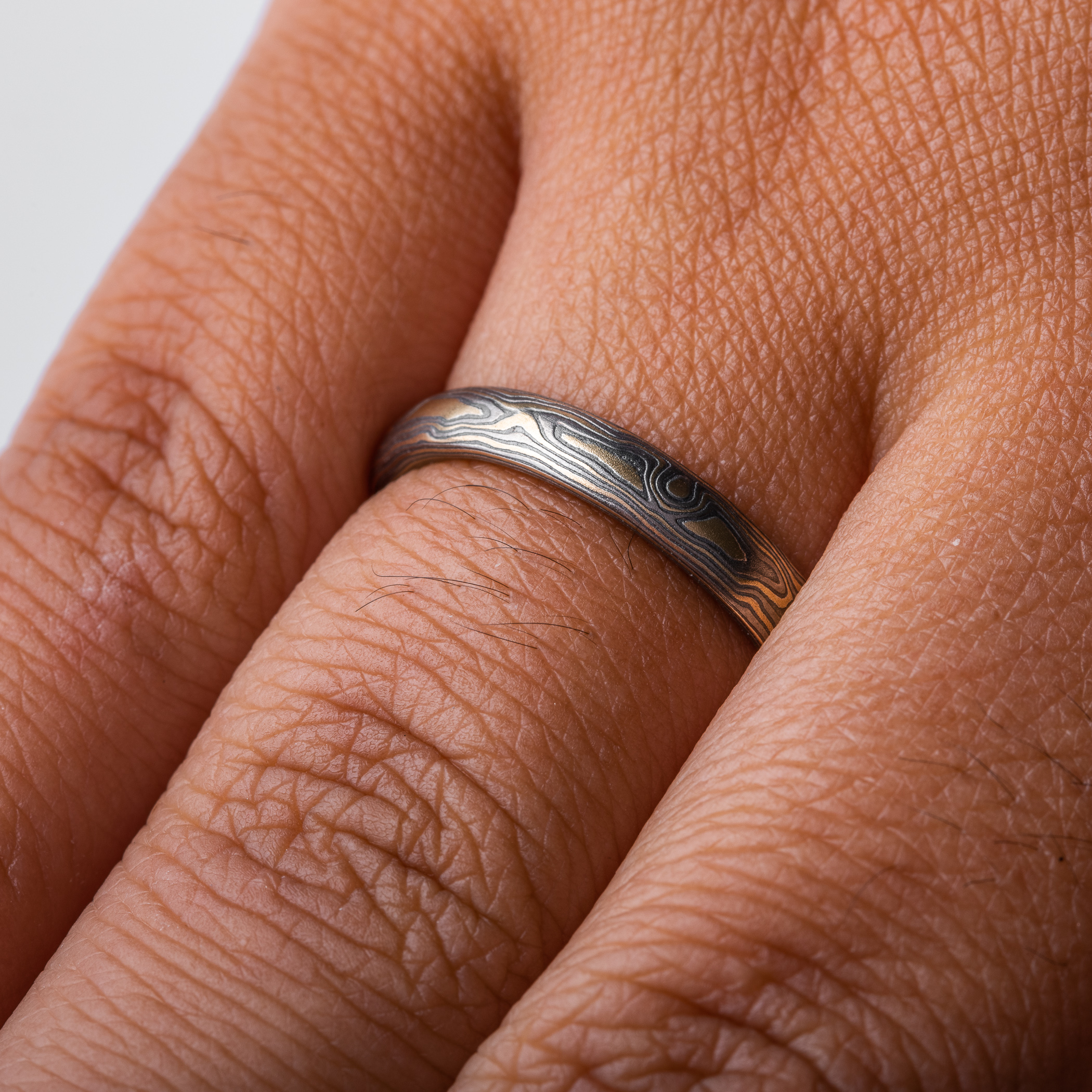 mokume gane woodgrain patterned ring made with yellow gold, palladium (dark gray) and oxidized silver (black)