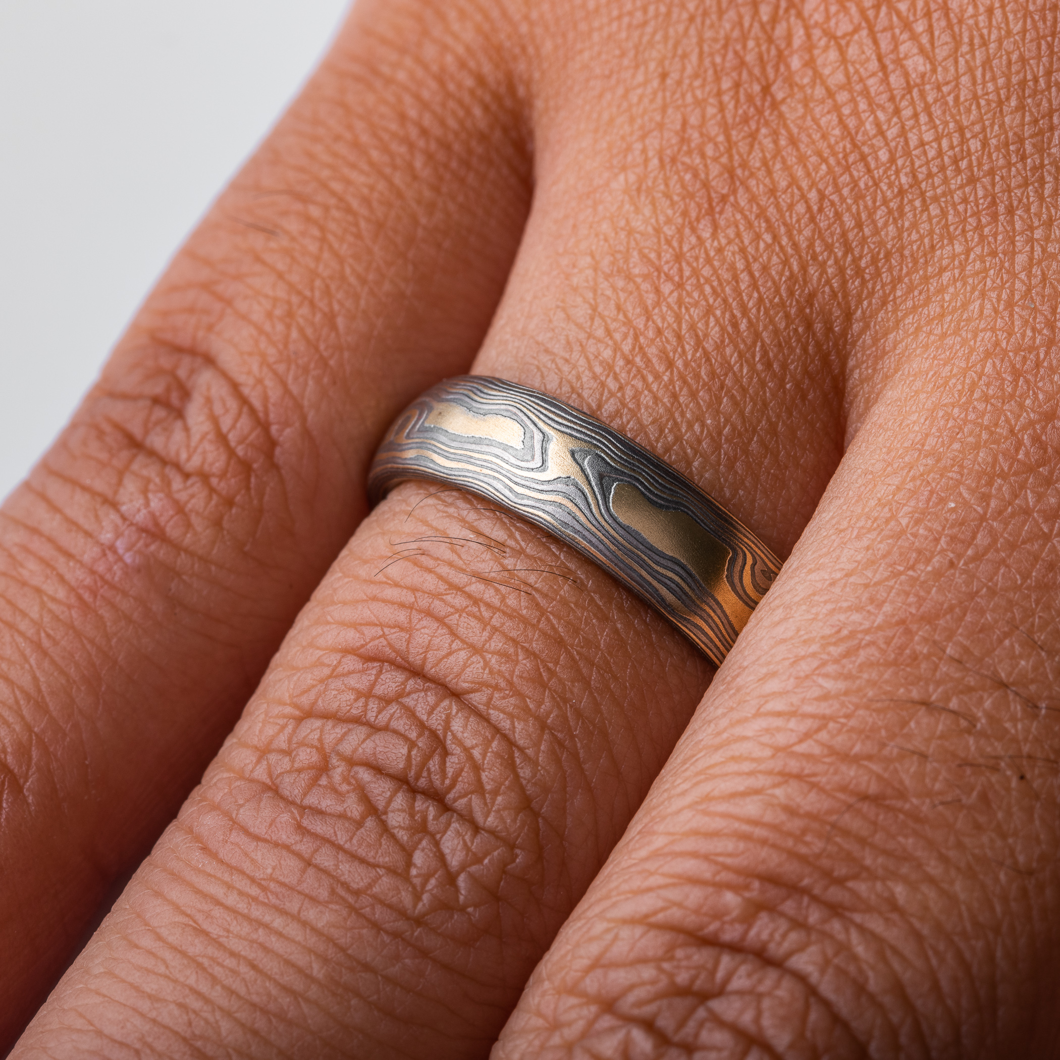 mokume gane woodgrain patterned ring made with yellow gold, palladium (dark gray) and oxidized silver (black)