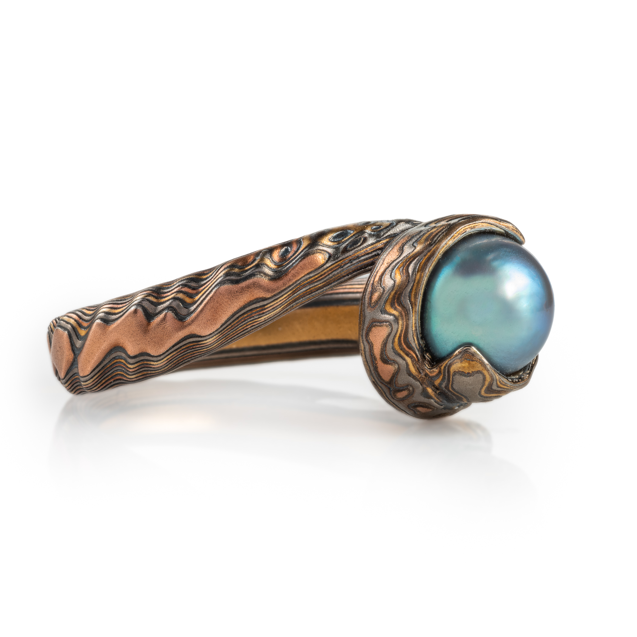 custom blue pearl in a swirled of bypass setting with woodgrain metal all around the pearl holding it in a circle