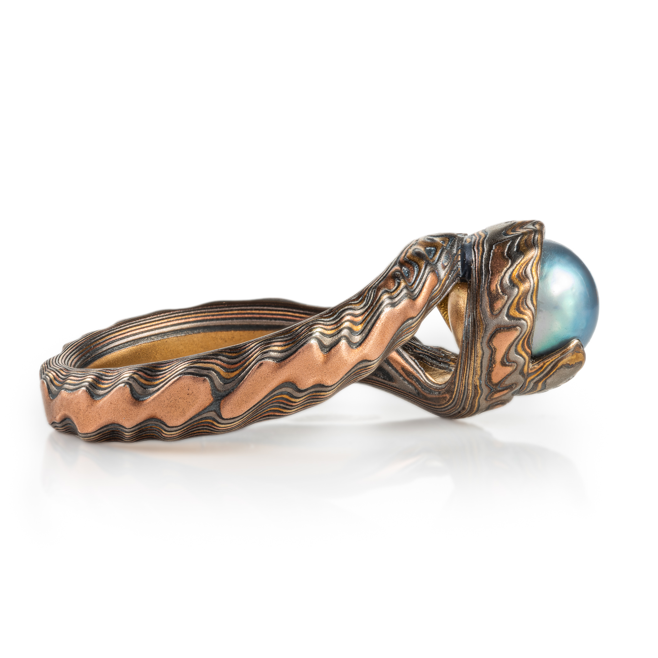custom blue pearl in a swirled of bypass setting with woodgrain metal all around the pearl holding it in a circle