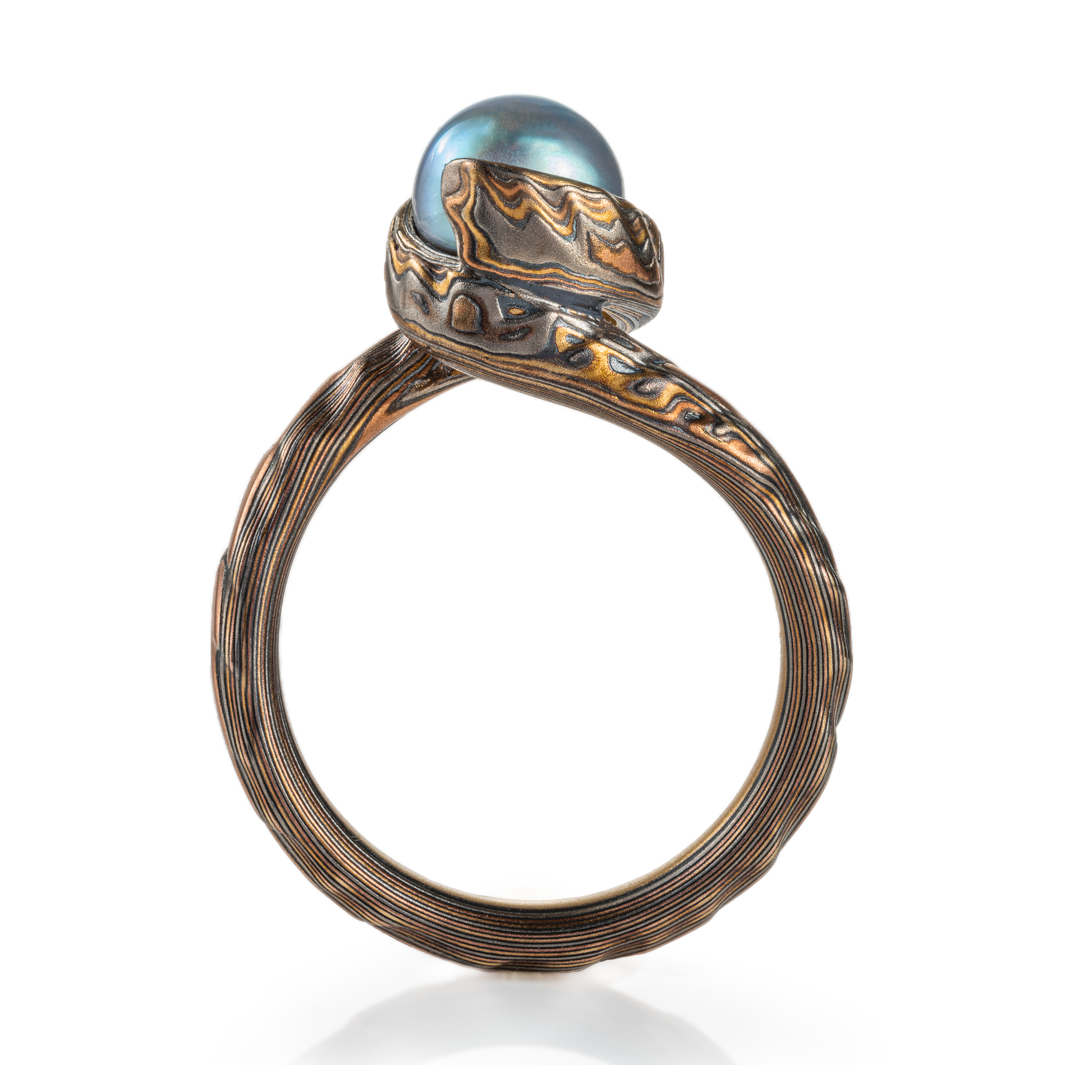 custom blue pearl in a swirled of bypass setting with woodgrain metal all around the pearl holding it in a circle