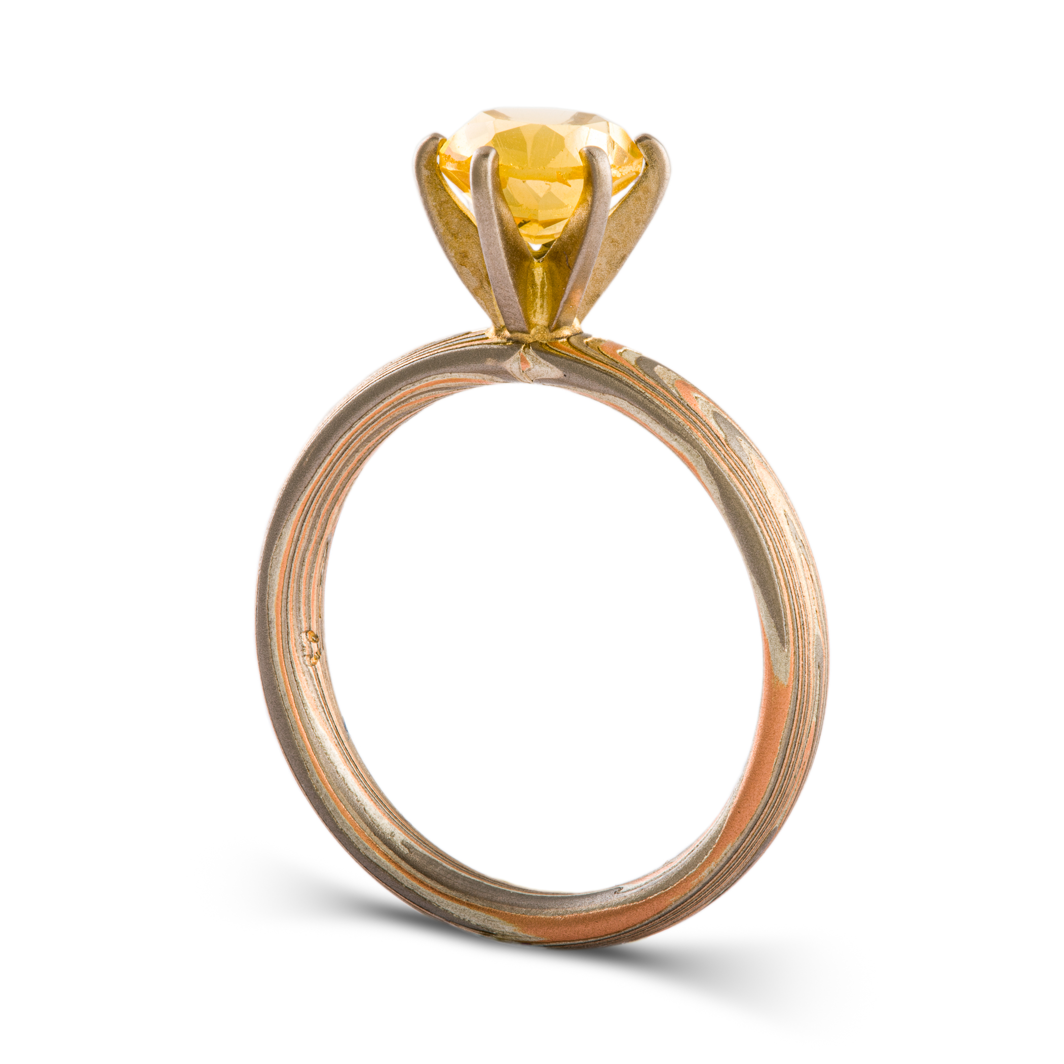 Mokume gane engagement style ring patterned with layers of red gold, palladium and silver, with a yellow stone set in prongs.