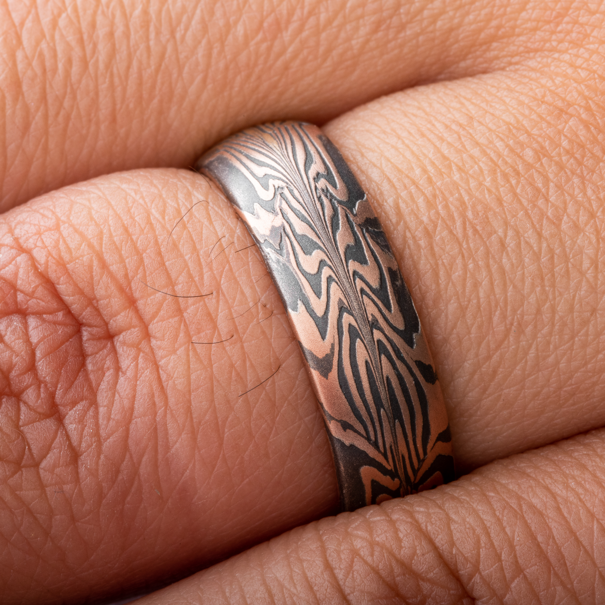 Uniquely patterned mokume gane ring in half red gold, half yellow gold, with oxidized silver.