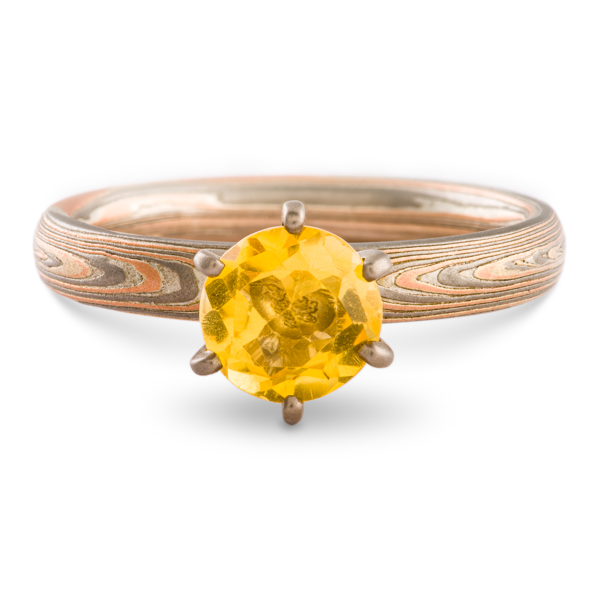 Mokume gane engagement style ring patterned with layers of red gold, palladium and silver, with a yellow stone set in prongs.