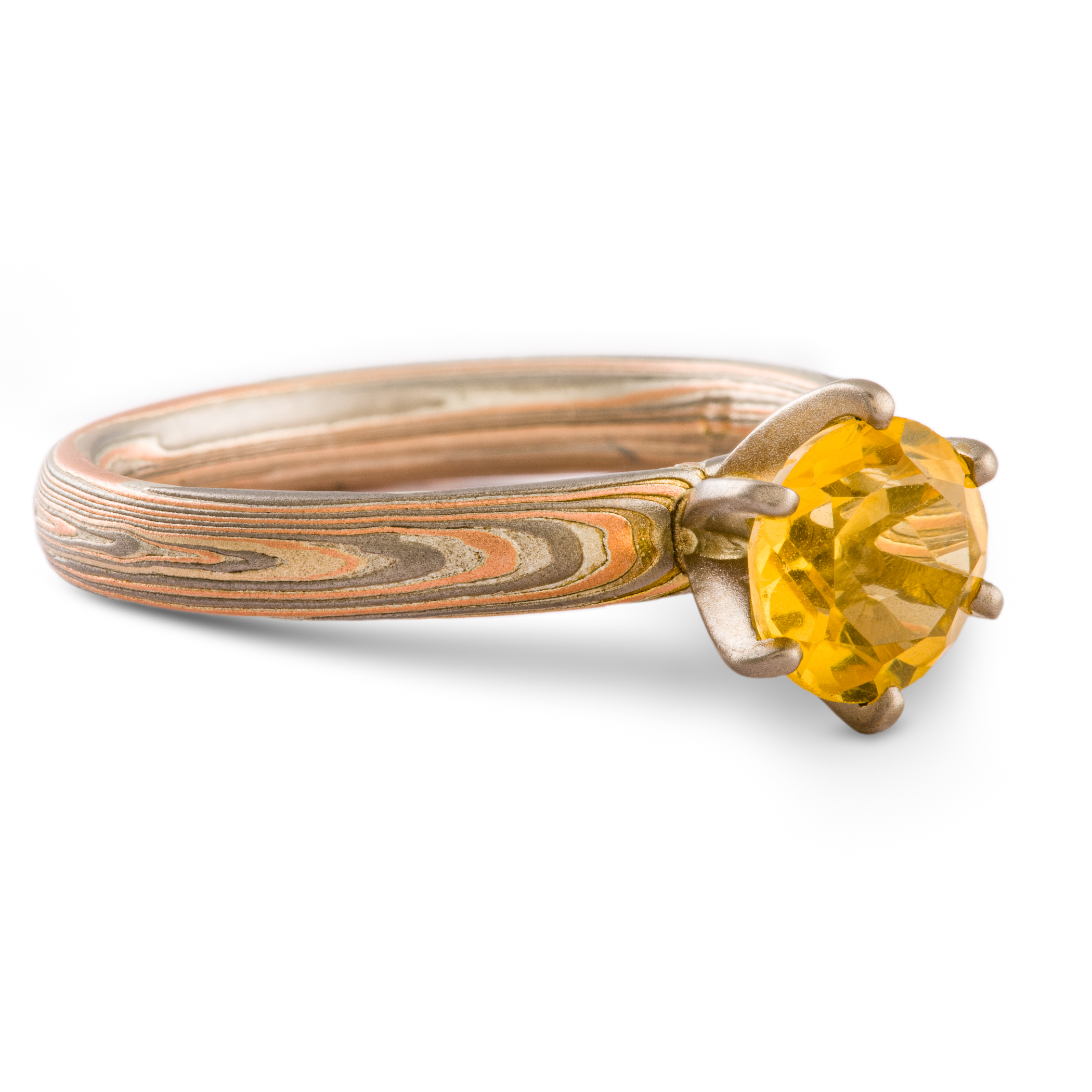 Mokume gane engagement style ring patterned with layers of red gold, palladium and silver, with a yellow stone set in prongs.