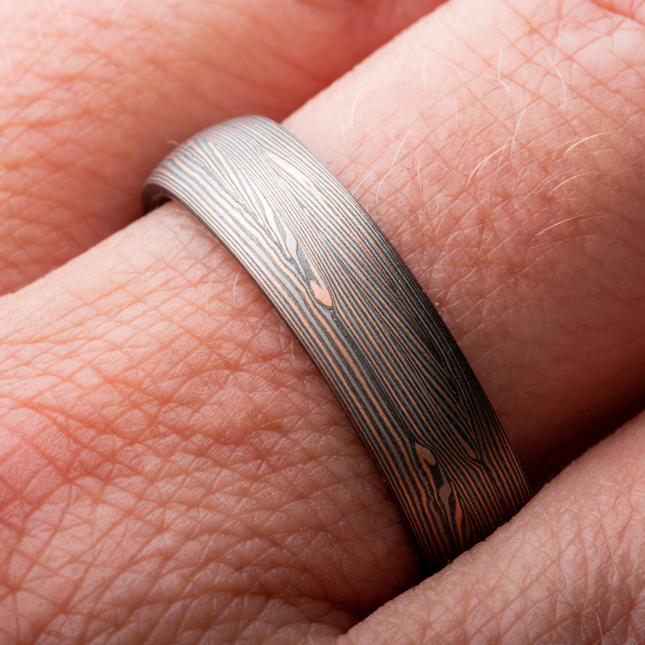 Mokume gane ring made in Arn Krebs Flow pattern made in a linear style with flowing fine lines. Made with red gold, palladium and oxidized silver.