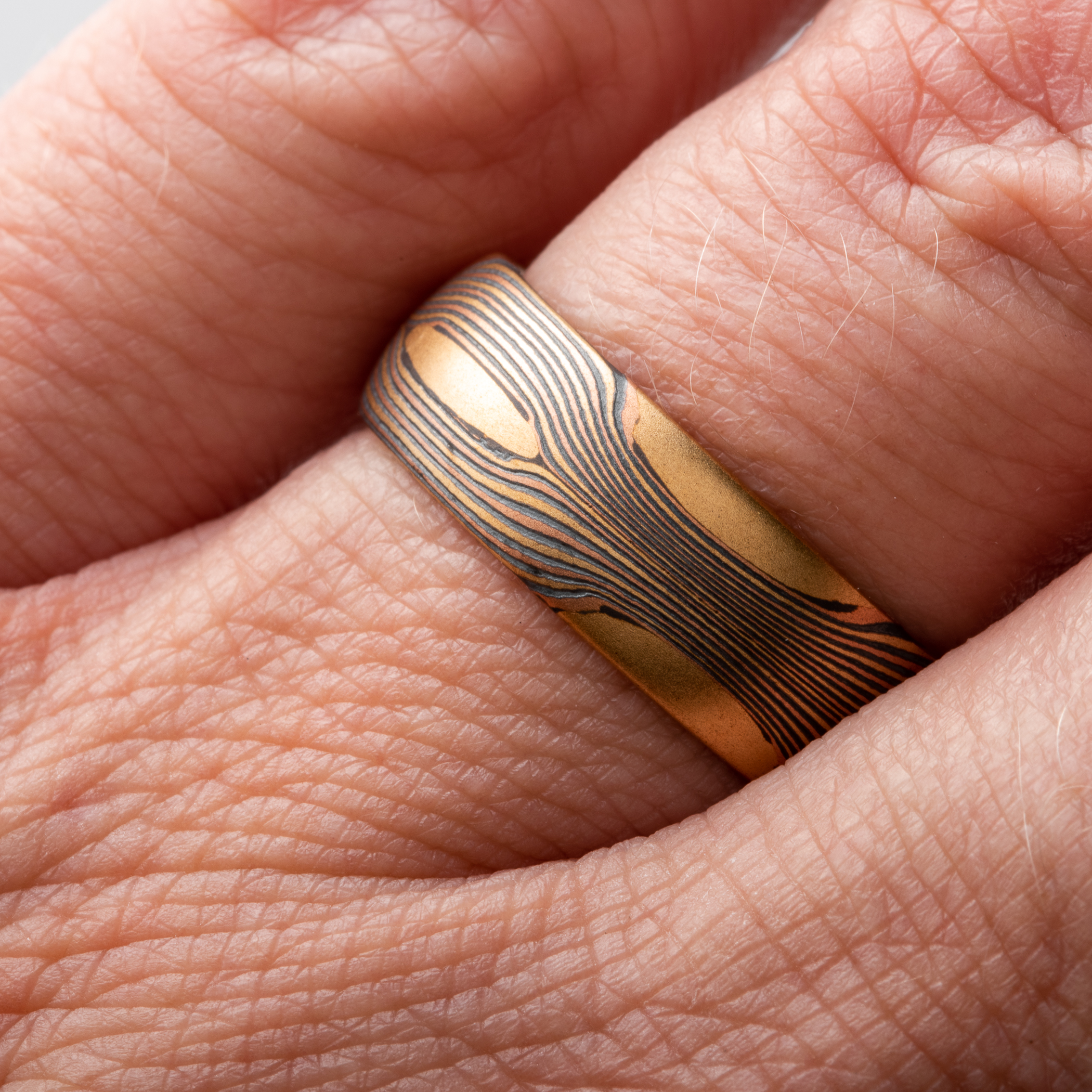 Arn Krebs Mokume Gane patterned ring, made with thin flowing lines of gold with yellow gold patches interspersed.