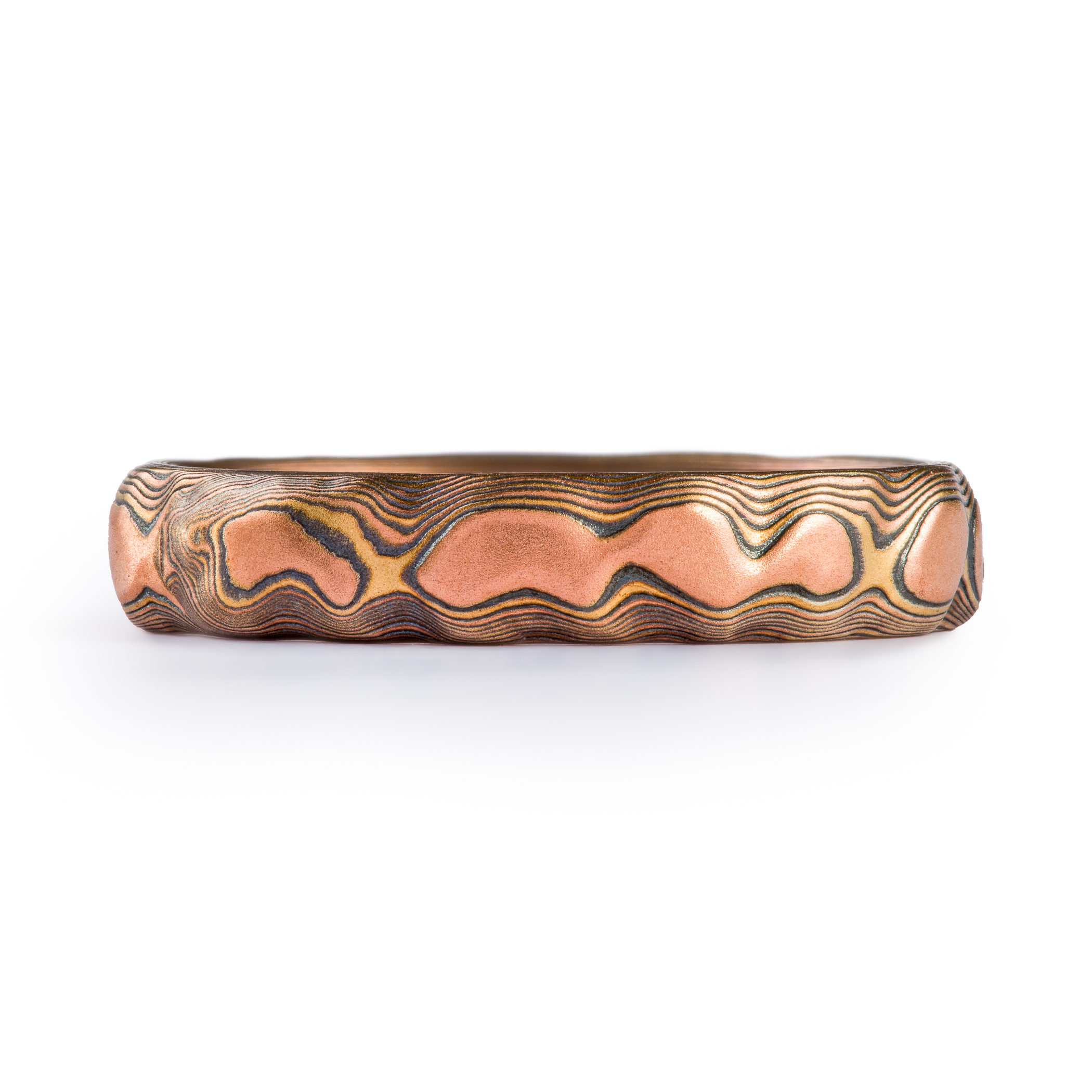 Textured red gold mokume gane ring, with three flush set stones, a slightly larger blue sapphire, flanked by small white stones.