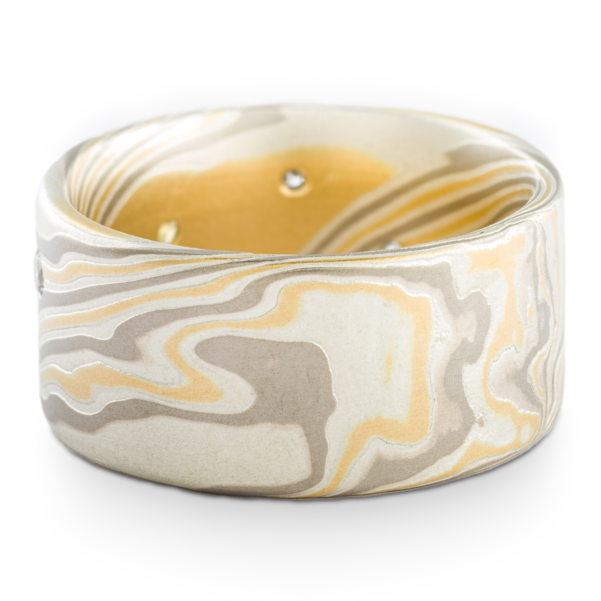 Mokume gane patterned ring made with yellow gold, palladium and silver, with small round yellow and white stones set into the wide, flat profile band.
