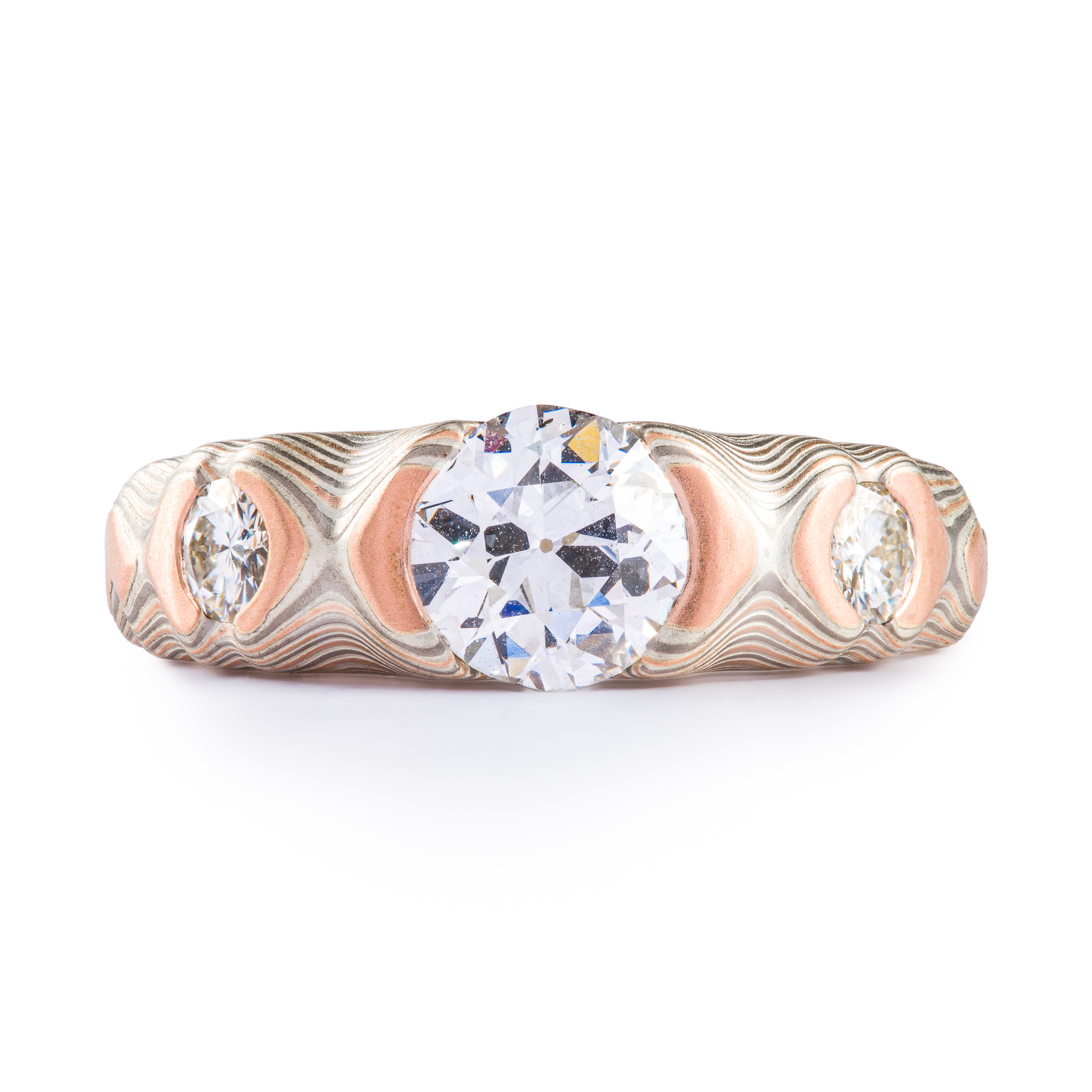 Diamond mokume gane cathedral style ring with one large center stone and two smaller side stones, made with red gold, palladium and silver.