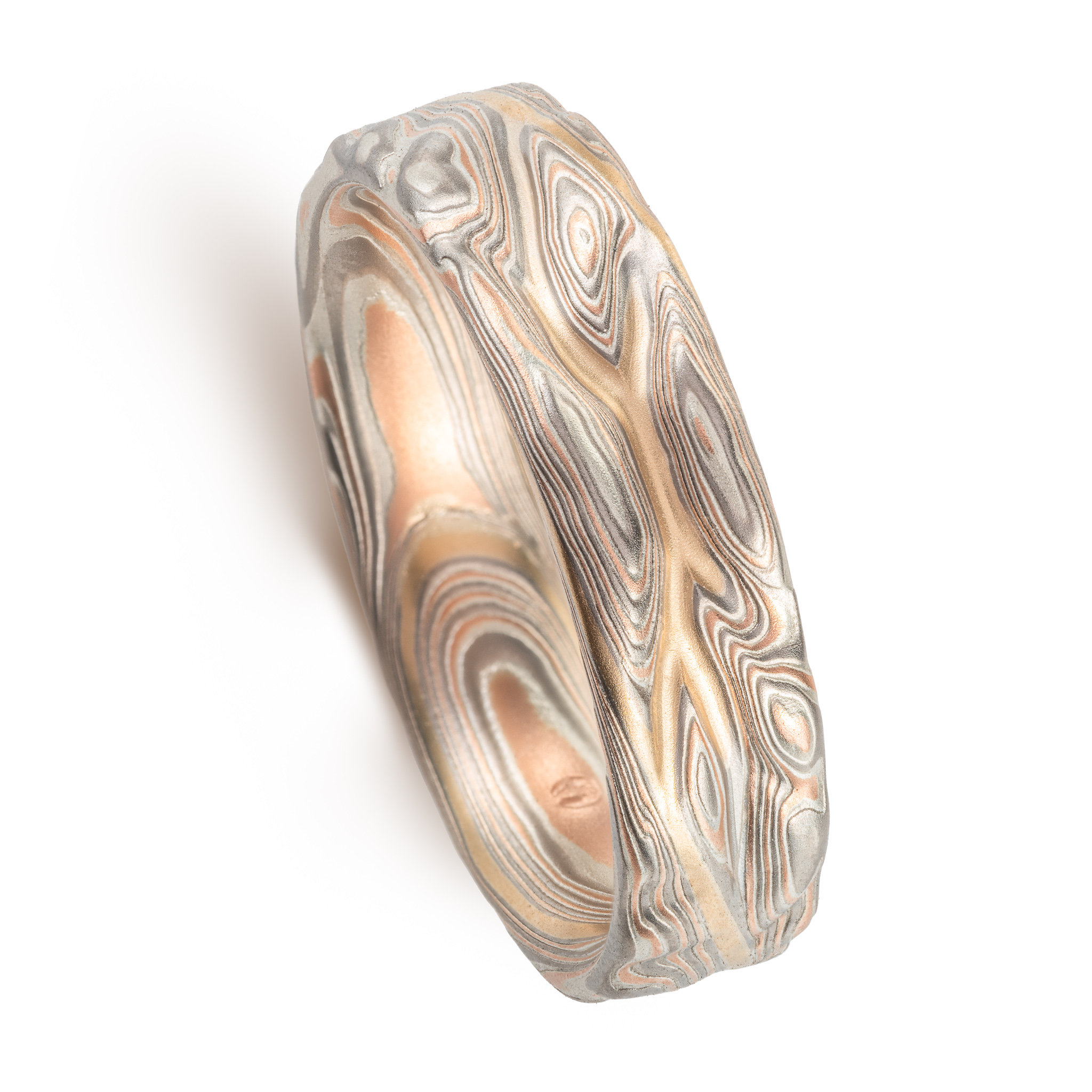 hand carved and handmade twisted metal and stripes of gold. iyellow gold , red gold, silver and palladium swirled metal. wide, carved ring for a man
