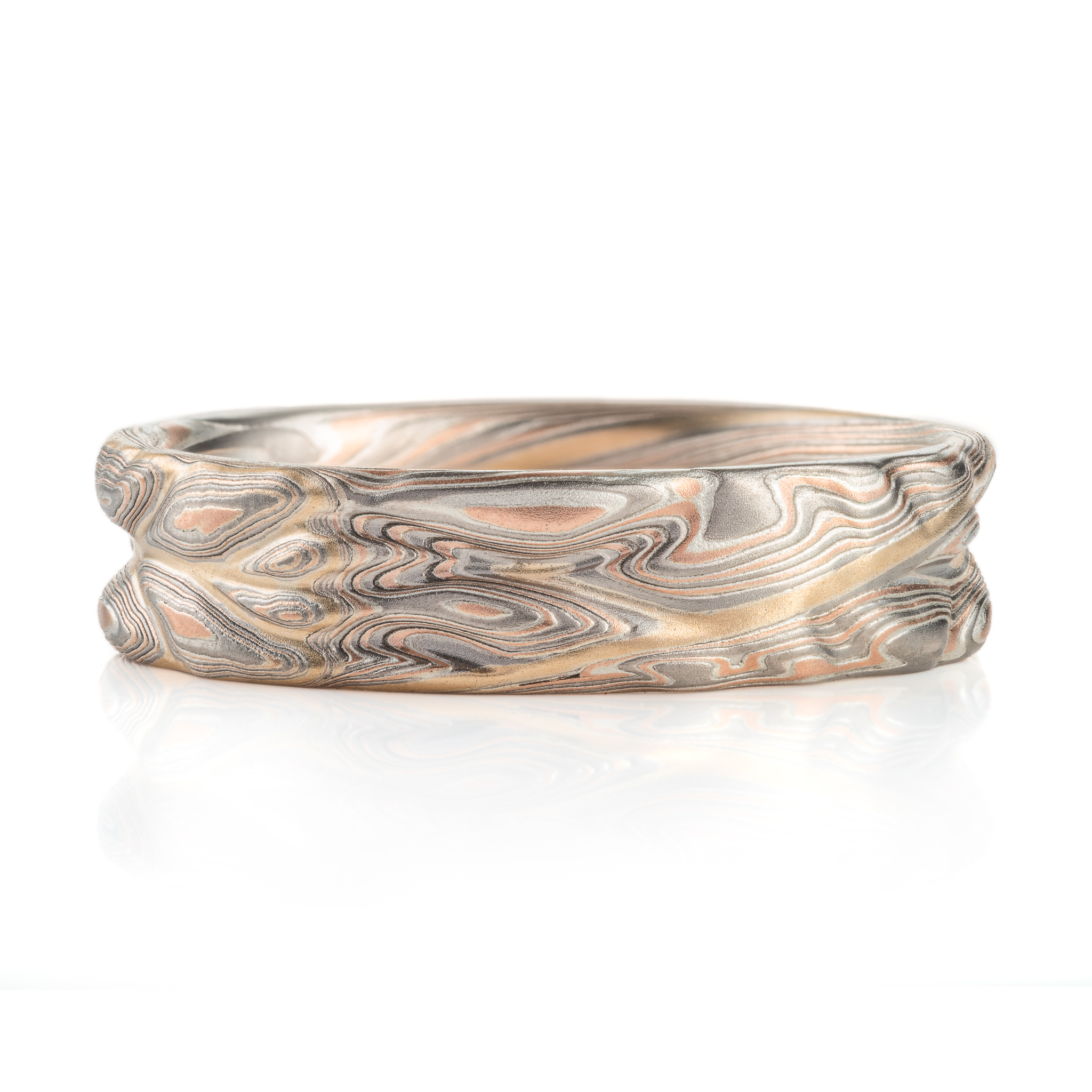hand carved and handmade twisted metal and stripes of gold. iyellow gold , red gold, silver and palladium swirled metal. wide, carved ring for a man