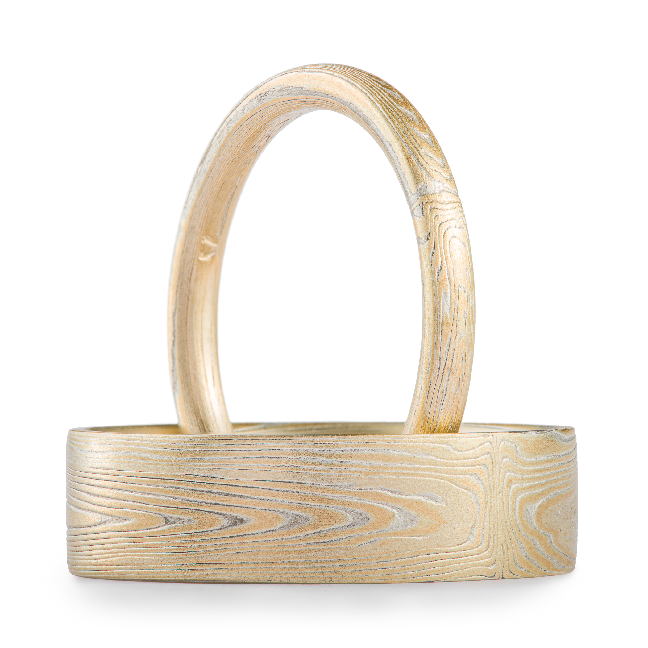 Arn Krebs mokume gane rings, one narrow and one wide, patterned in a subtle linear style in his vortex pattern. Made with yellow gold and silver.