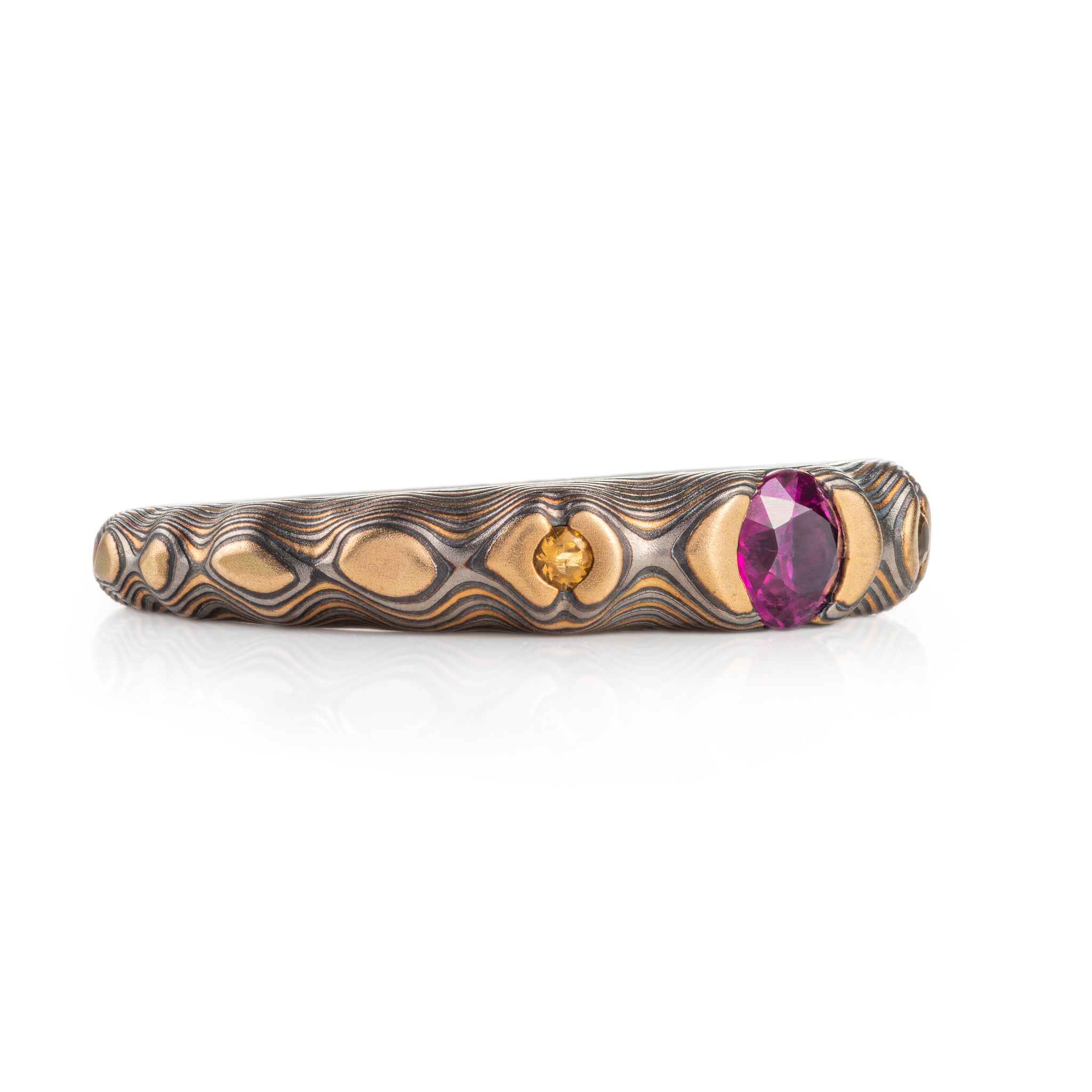 pink purple sapphire with cognac diamonds set in a mokume band of yellow gold, silver and palladium. the stones are set in yellow gold islands