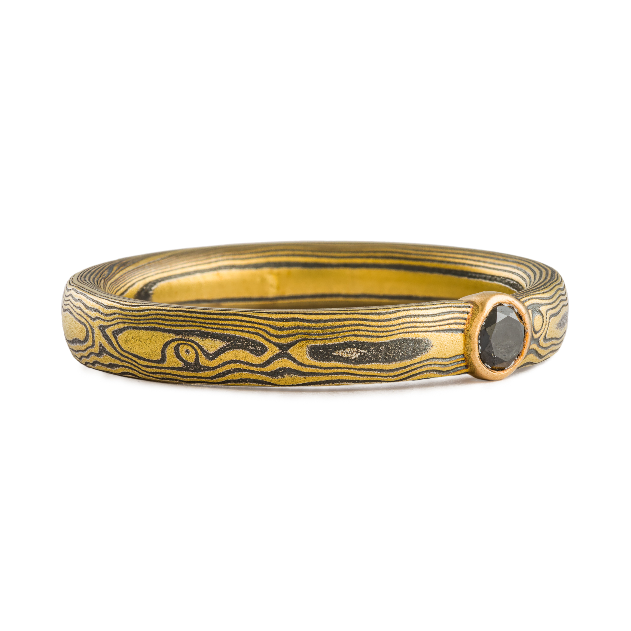 mokume gane ring by arn krebs in spark metal palette and woodgrain pattern with bezel set black diamond
