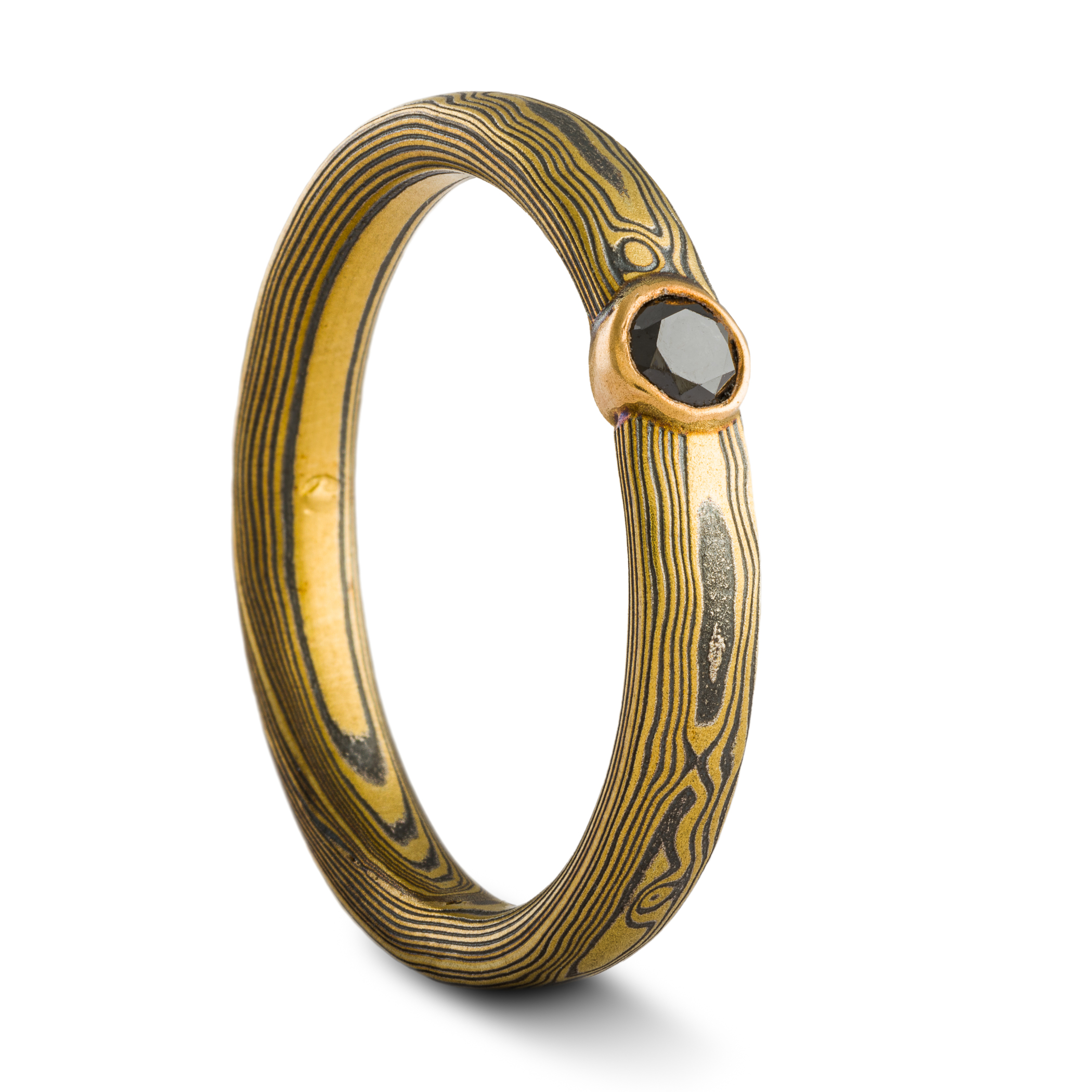 mokume gane ring by arn krebs in spark metal palette and woodgrain pattern with bezel set black diamond