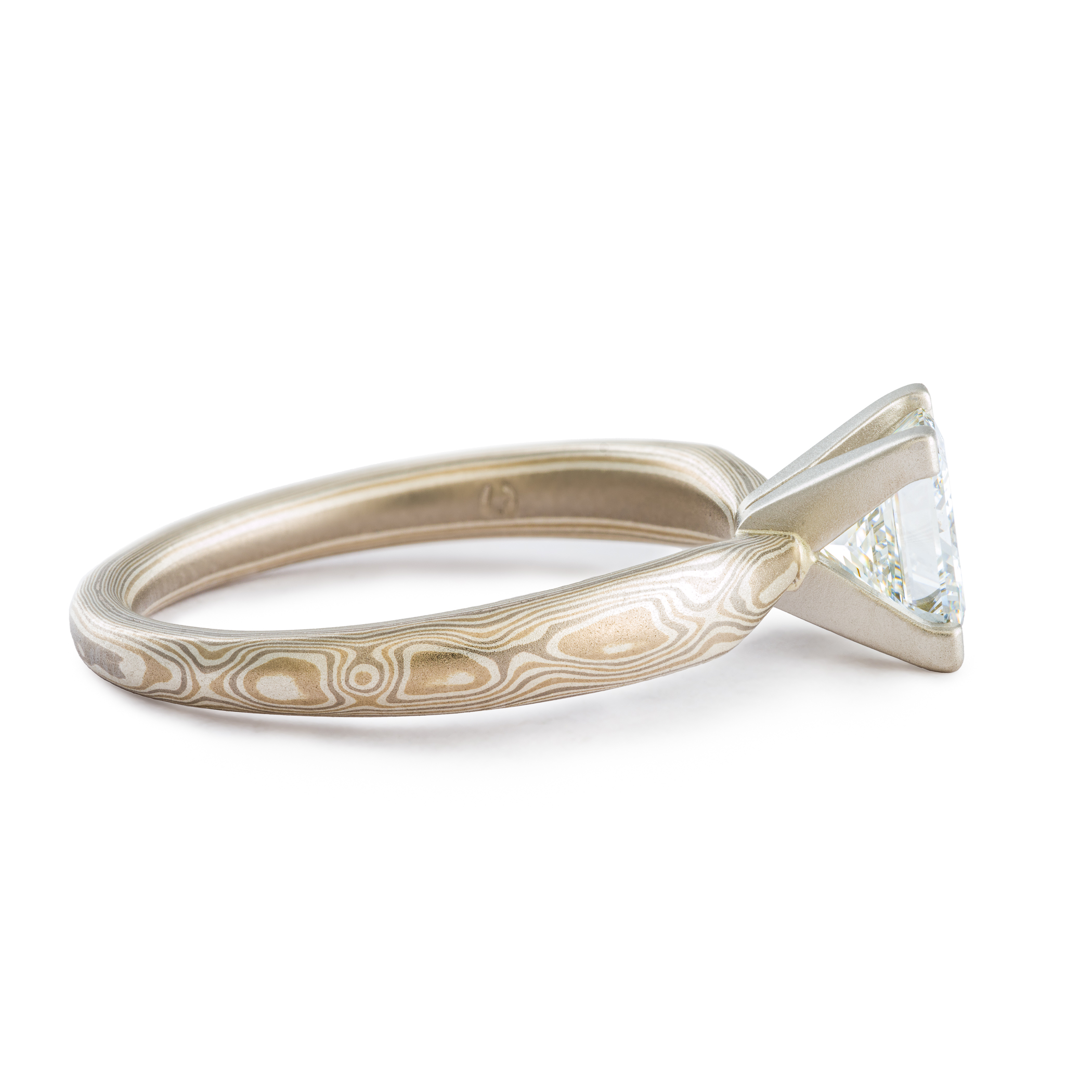 solitaire style mokume gane engagement ring with square diamond set in prongs, ring has an overall silvery palette and a woodgrain style