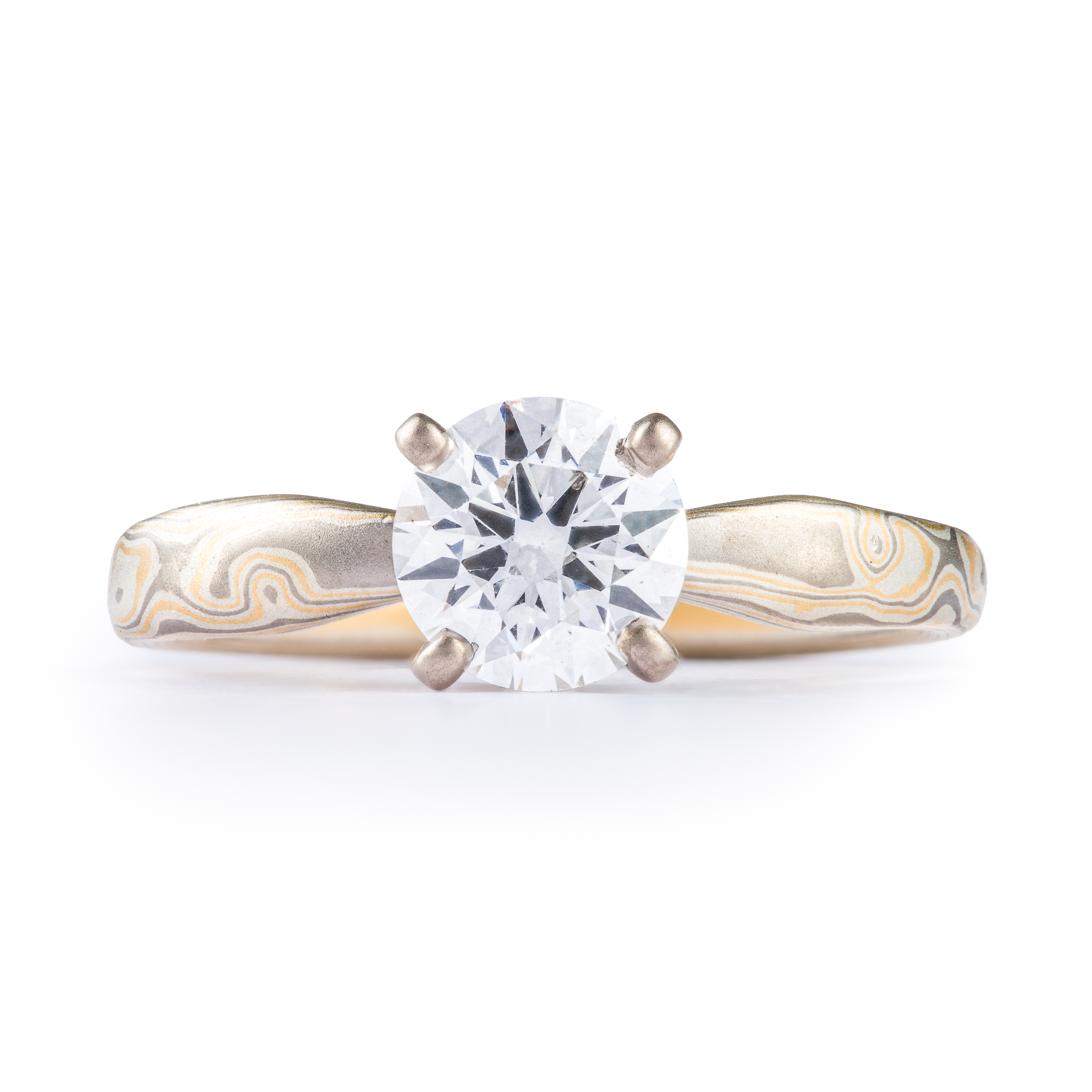 Arn Krebs mokume engagement ring, patterned in a woodgrain style with yellow gold and silver and gray metals, with a solitaire round diamond set in prongs.