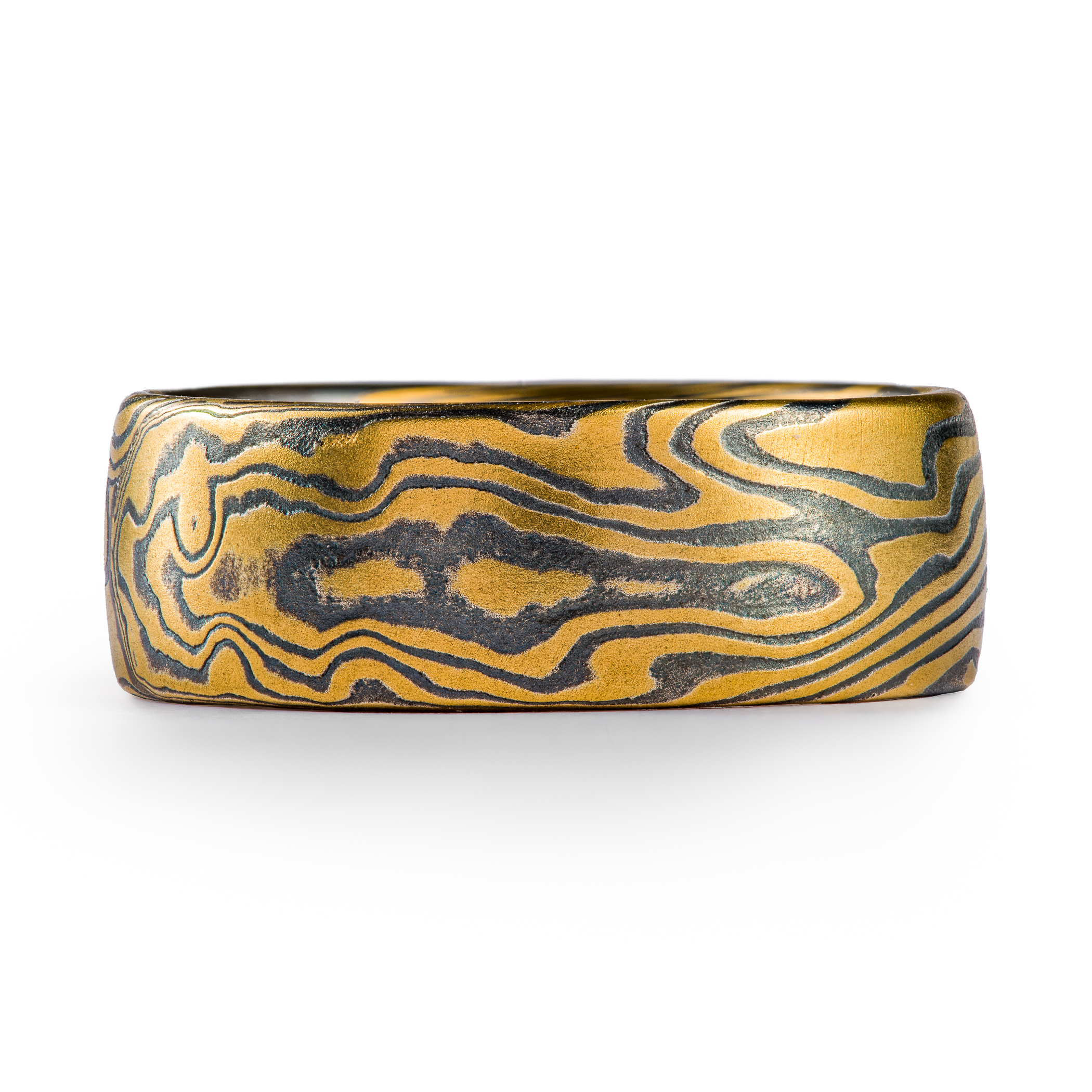 Wide men's style mokume gane ring made with layers of yellow gold and oxidized silver (black), in a dynamic twisting pattern.