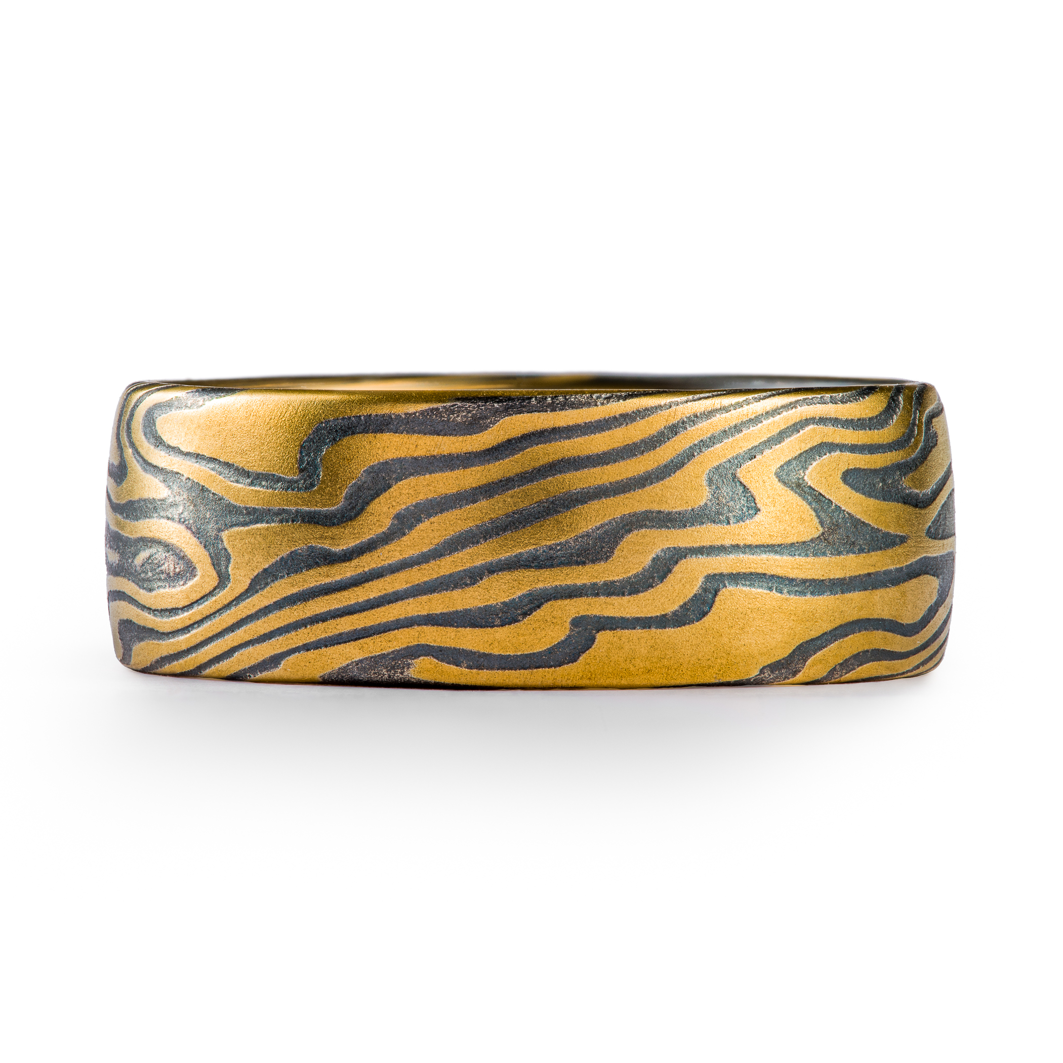 Wide men's style mokume gane ring made with layers of yellow gold and oxidized silver (black), in a dynamic twisting pattern.