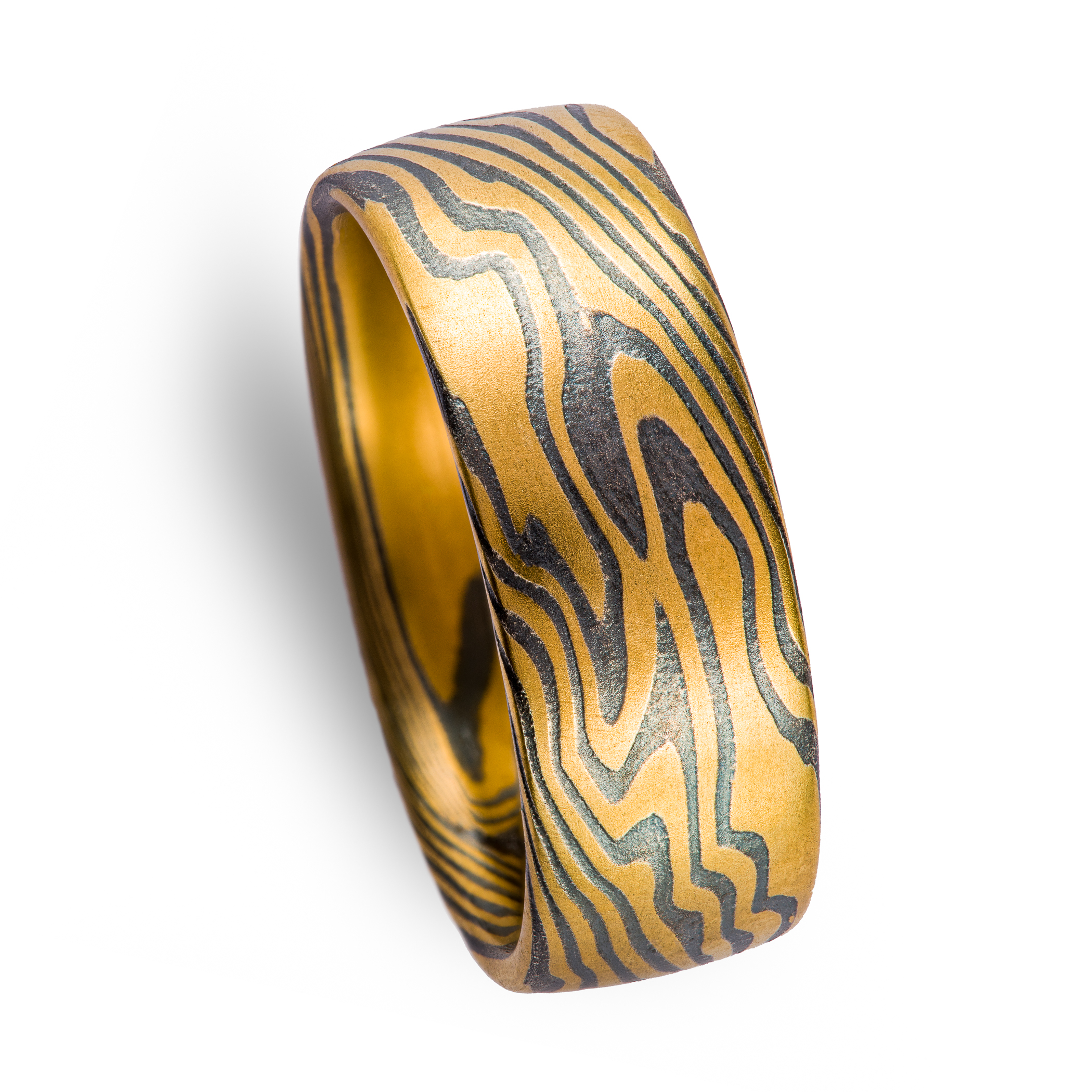 Wide men's style mokume gane ring made with layers of yellow gold and oxidized silver (black), in a dynamic twisting pattern.