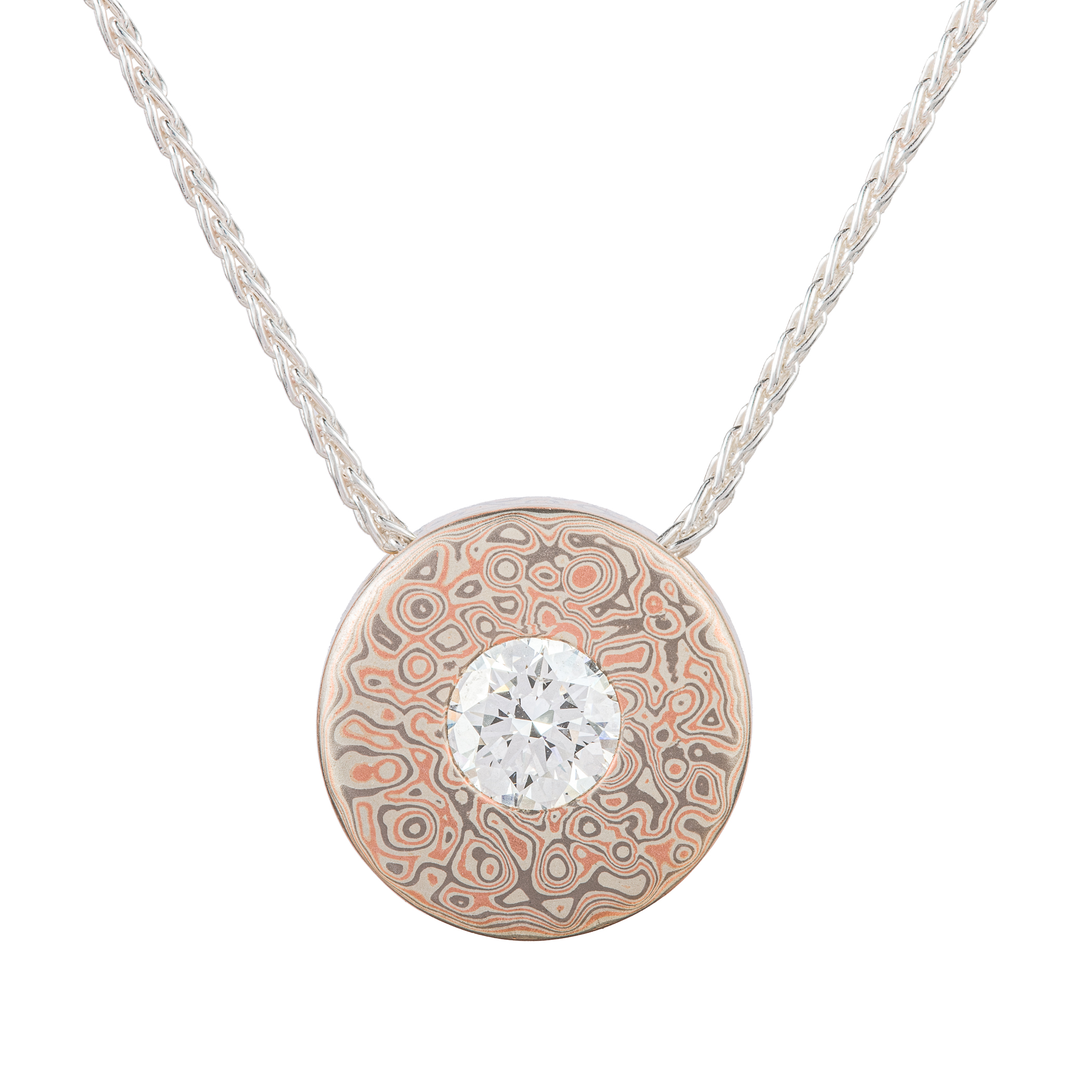 Small round pendant with a moissanite set in the center on a chain, patterned in a style that looks like raindrops on water.